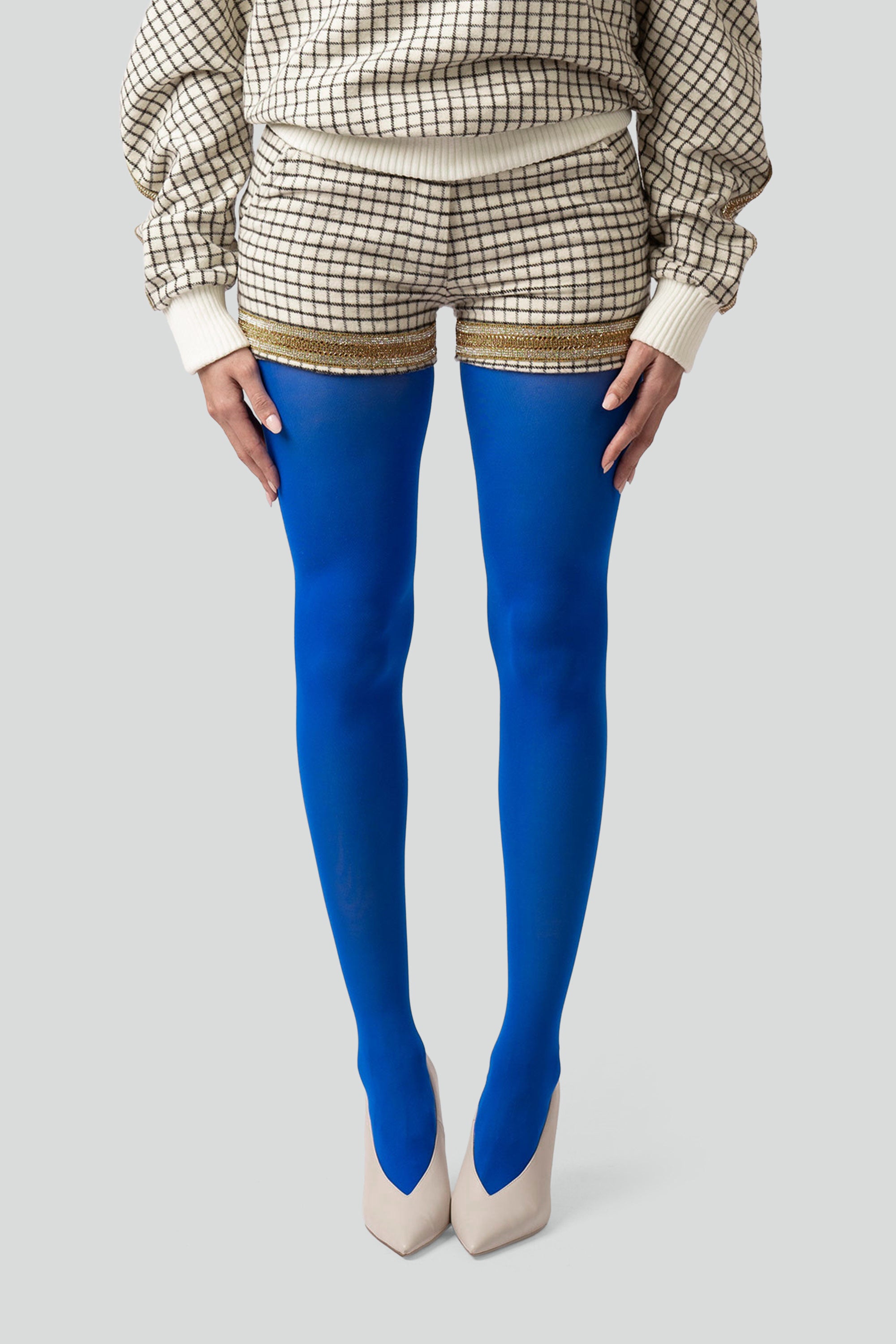 Person wearing blue tights and grid patterned shorts with a plain background