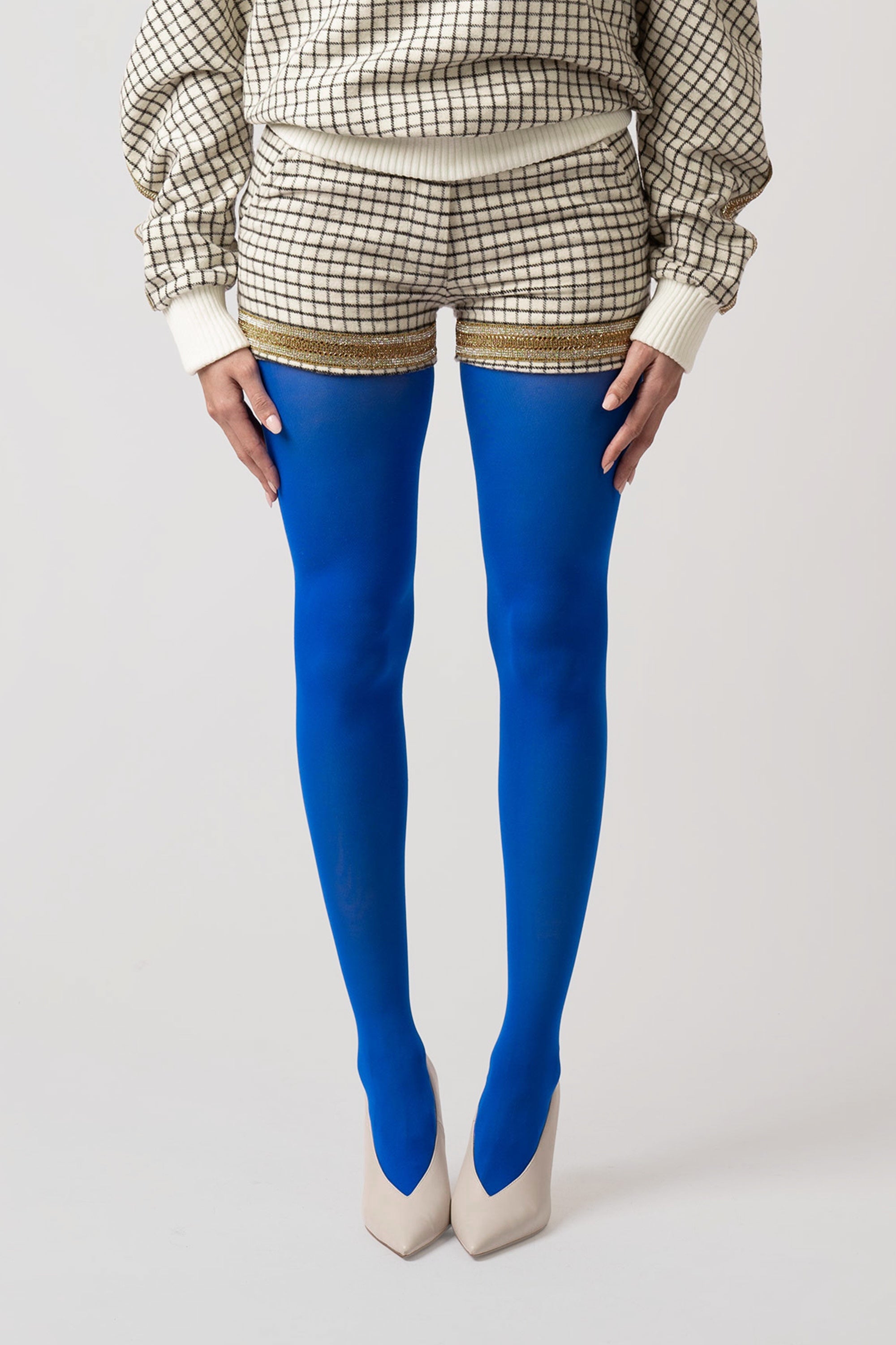 Person wearing blue tights and grid patterned shorts with a plain background