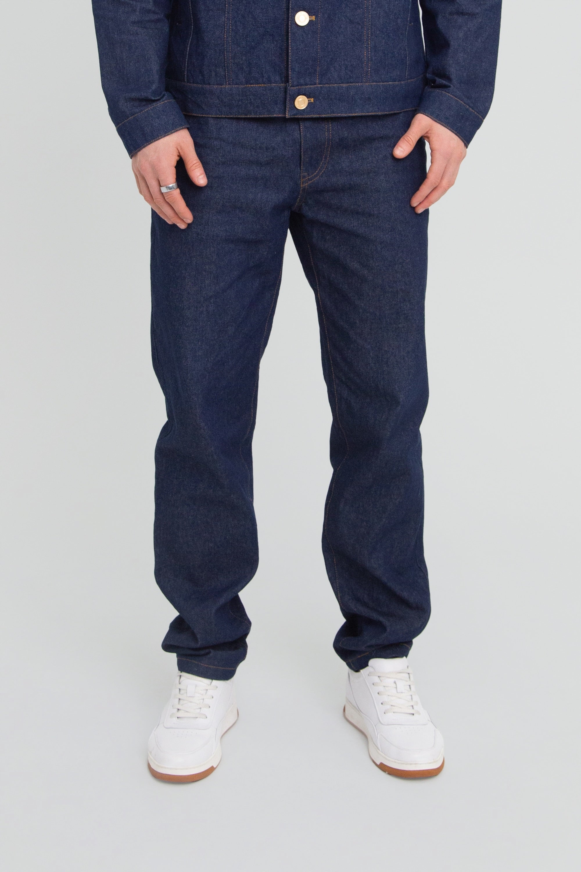 Person wearing a dark blue denim pants on a plain background