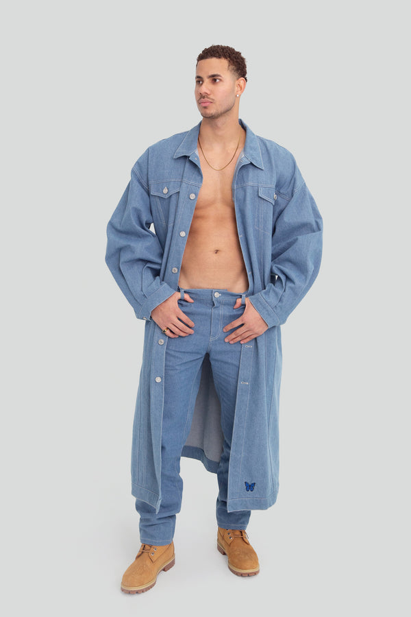 Man wearing a light wash oversized denim trench coat jacket featuring a structured longline silhouette and classic front button closures