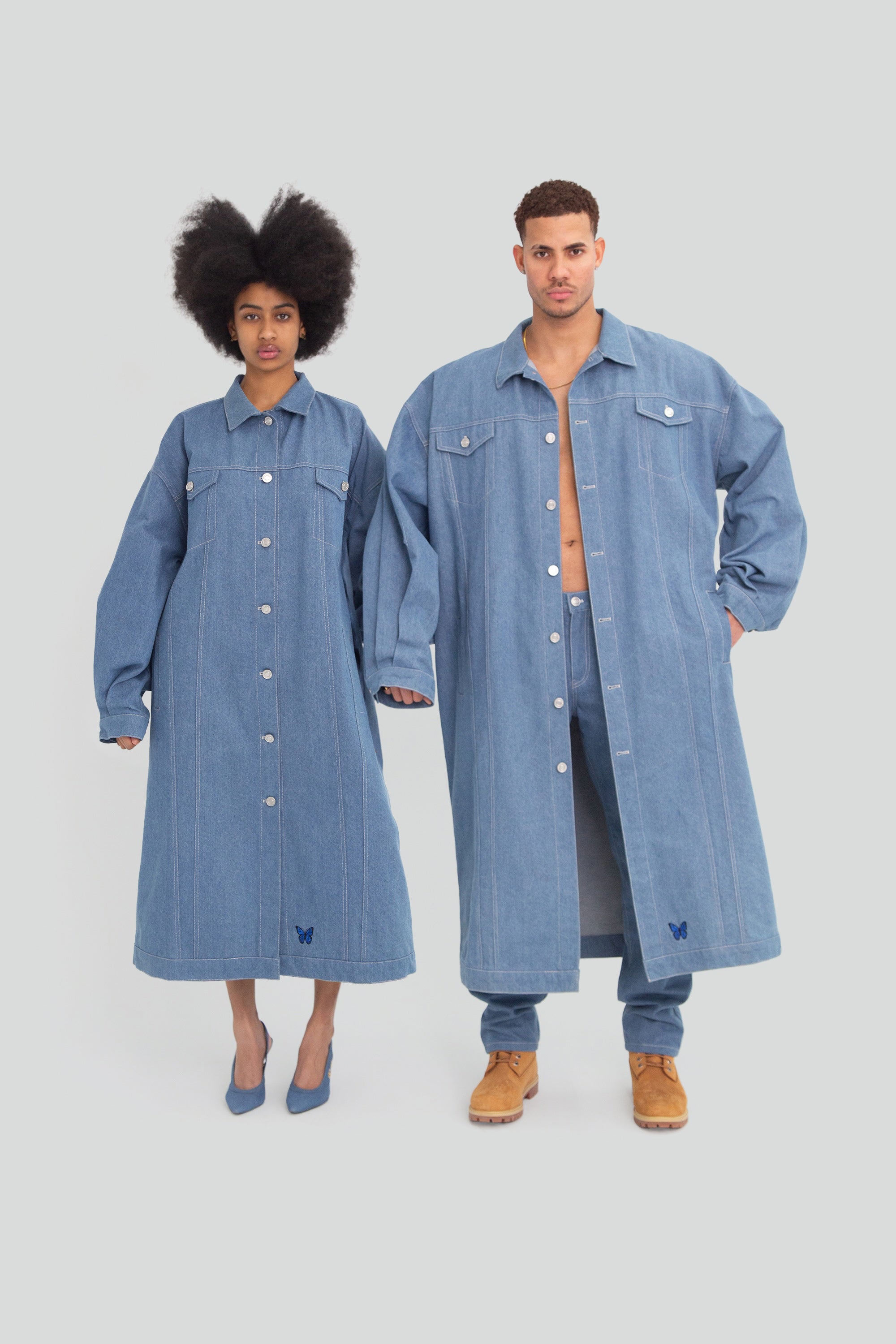Two people wearing matching blue denim jackets on a white background