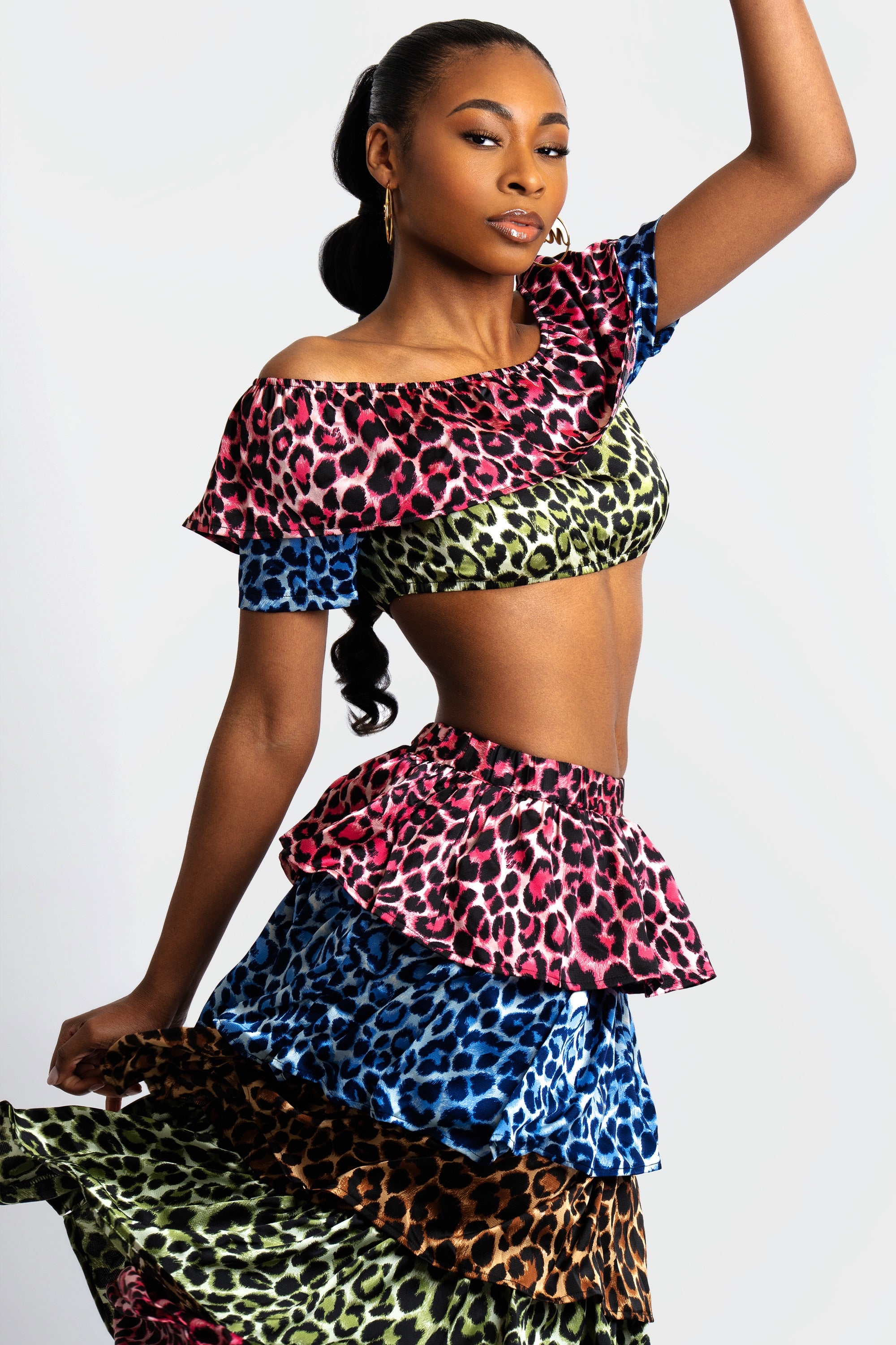 Woman wearing a colorful animal print tiered skirt and off-shoulder top on a white background