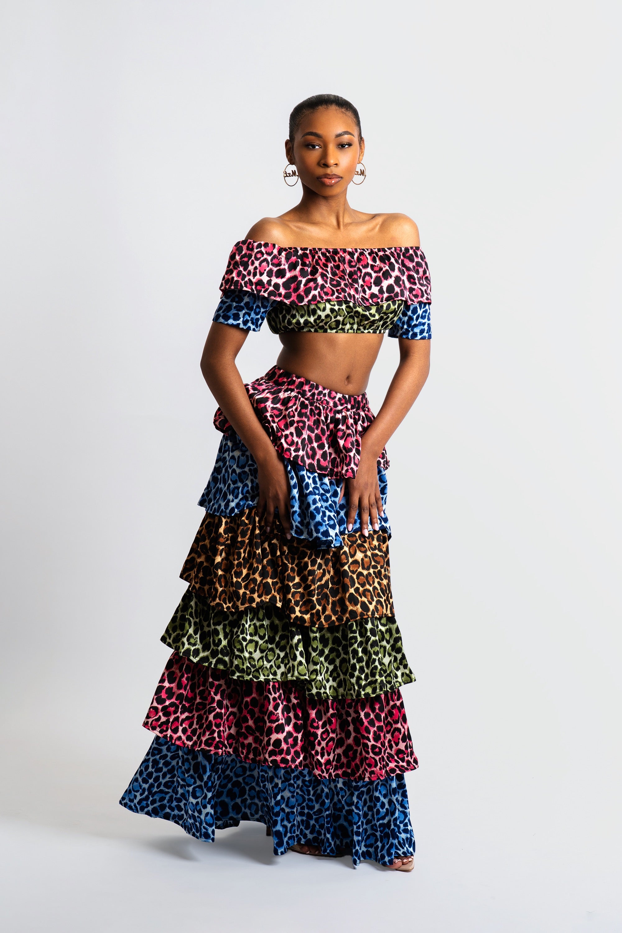 Woman wearing a colorful animal print tiered skirt and off-shoulder top on a white background