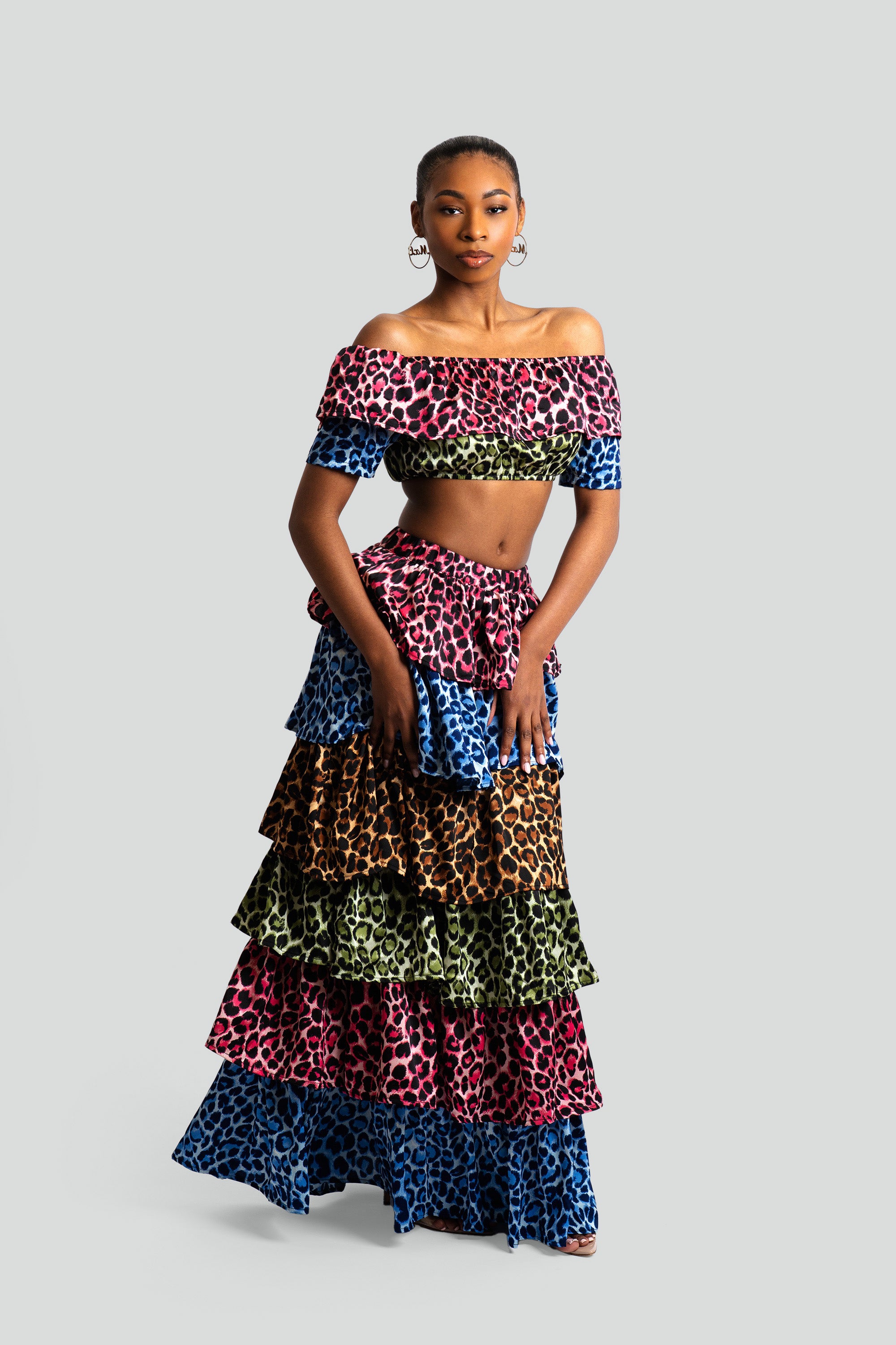 Woman wearing a colorful animal print tiered skirt and off-shoulder top on a white background