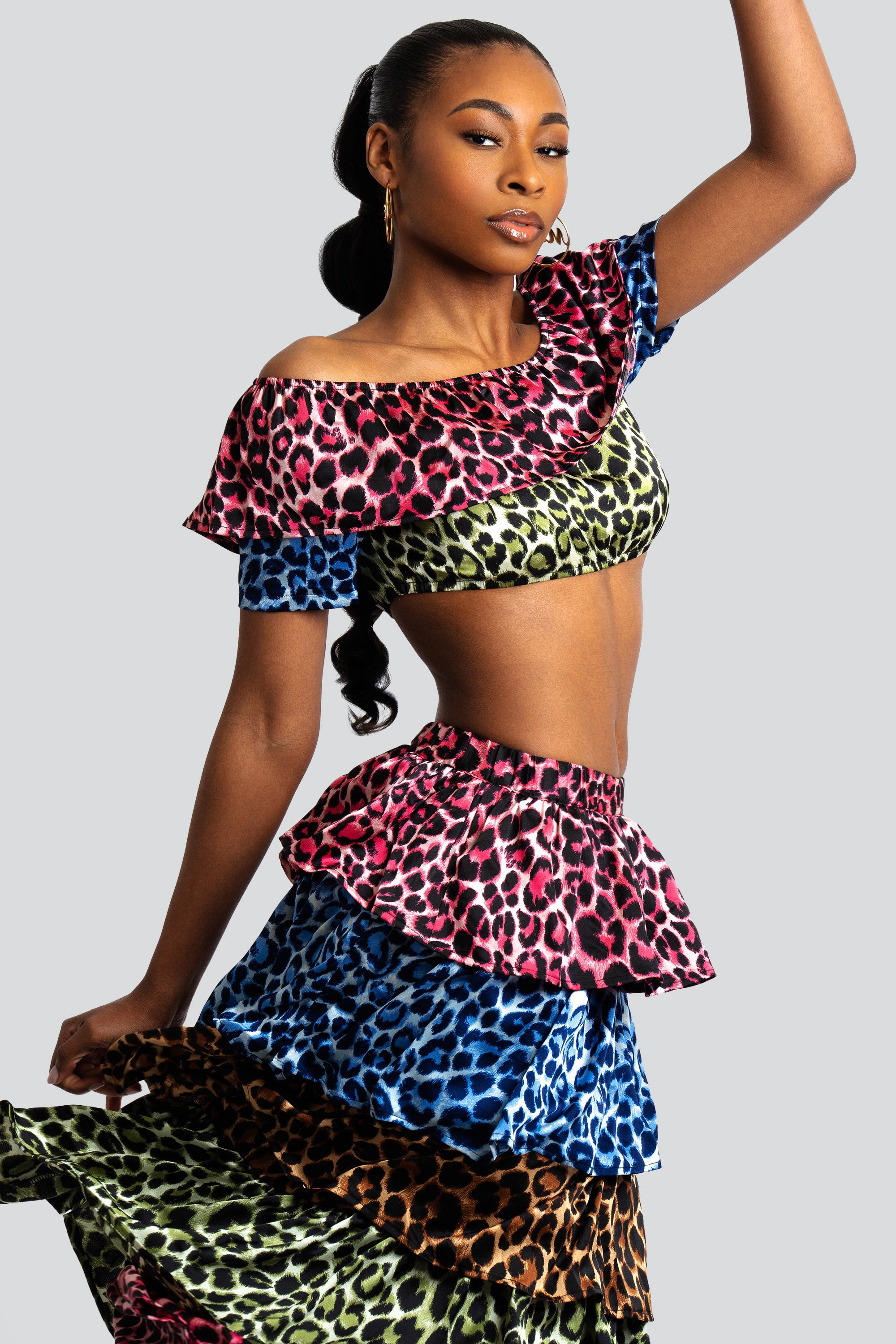 Woman wearing a colorful animal print tiered skirt and off-shoulder top on a white background