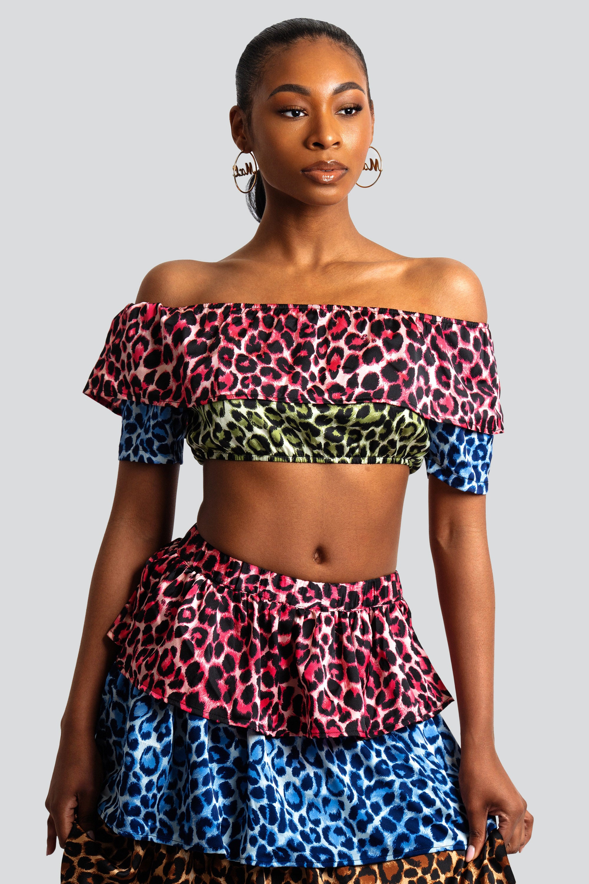 Woman wearing a colorful animal print tiered skirt and off-shoulder top on a white background
