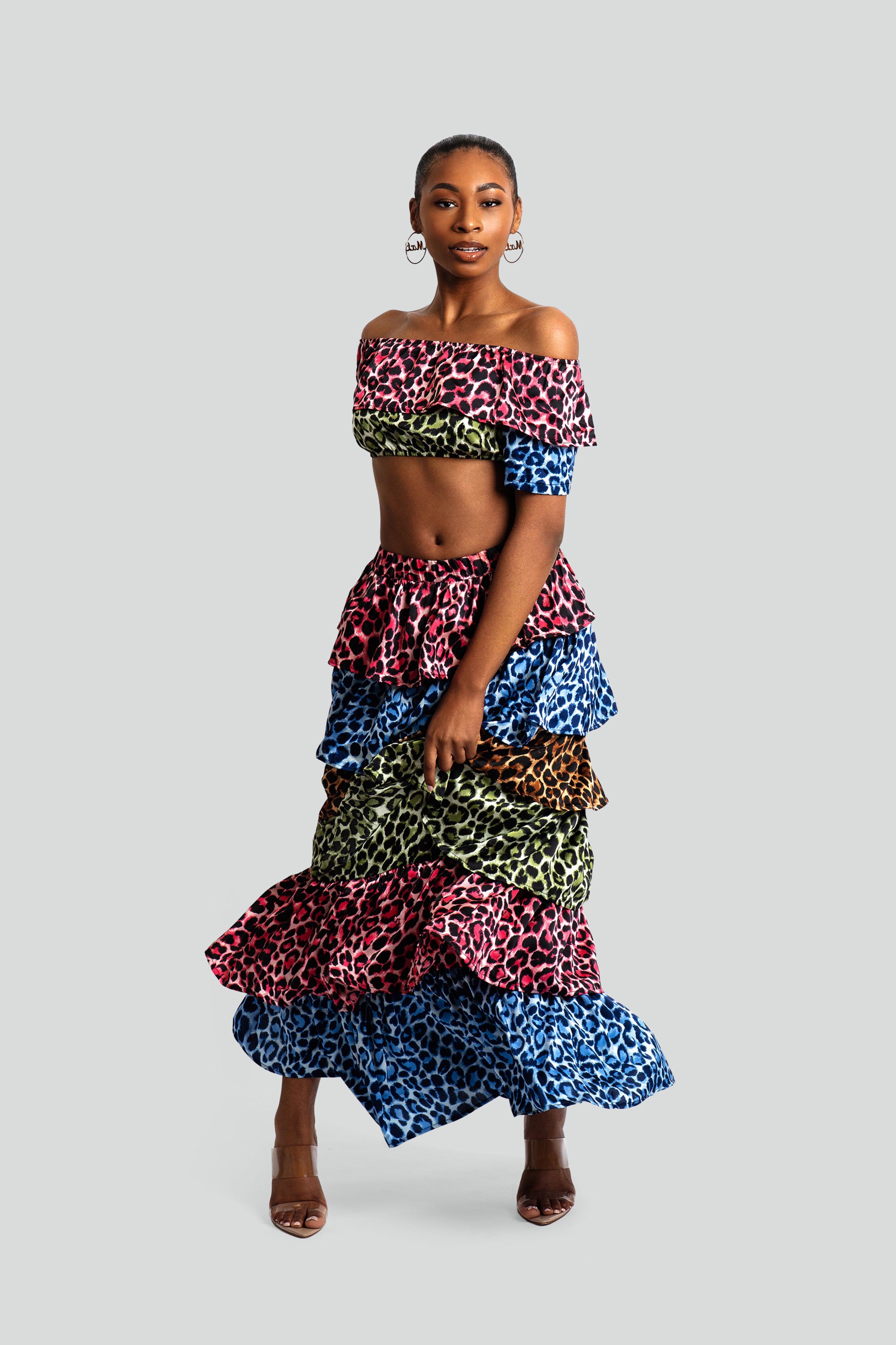 Woman wearing a colorful animal print tiered skirt and off-shoulder top on a white background