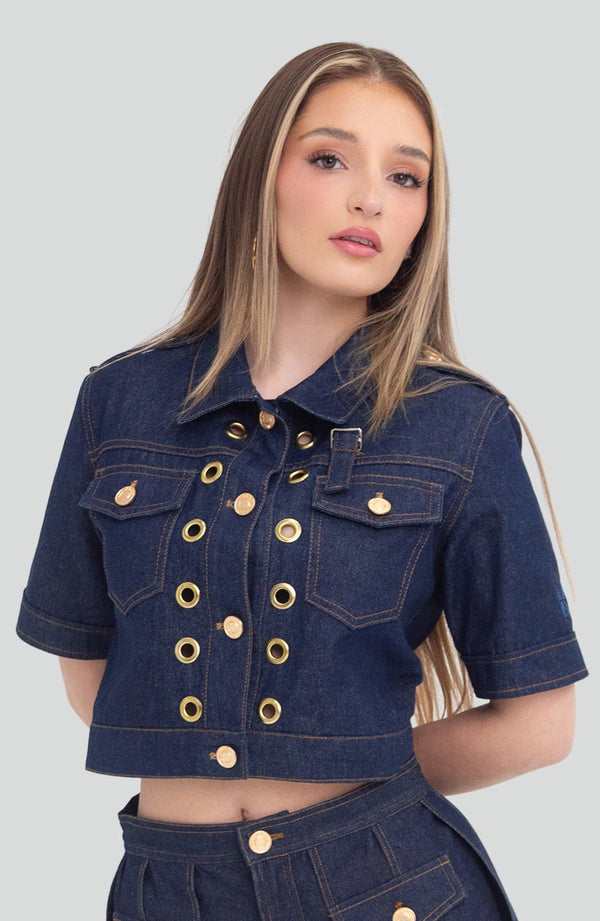 Woman styling a dark blue raw denim two piece crop top and high waisted pleated skirt set with an architectural design