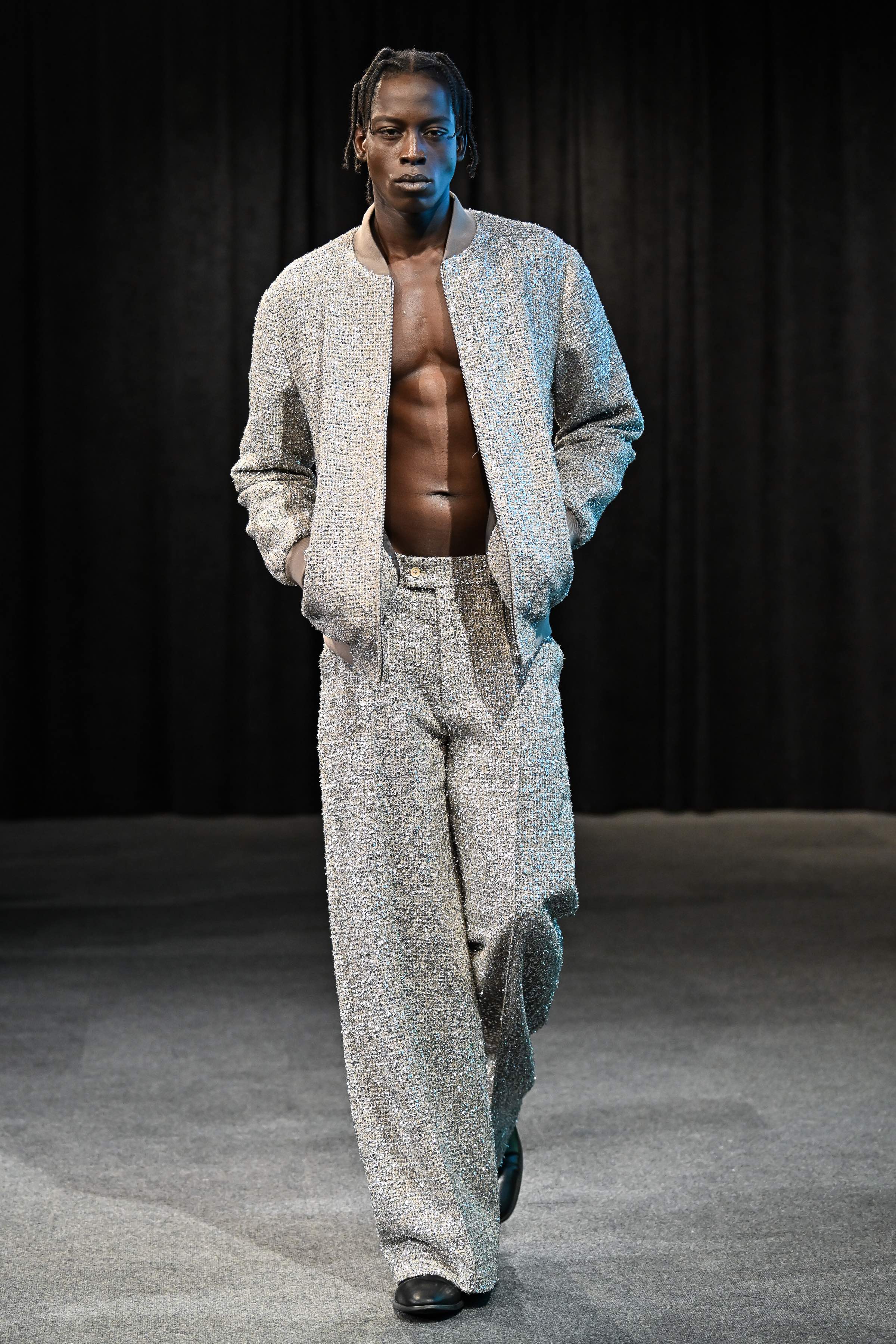 Man wearing a textured metallic tweed jacket and pants on a dark background