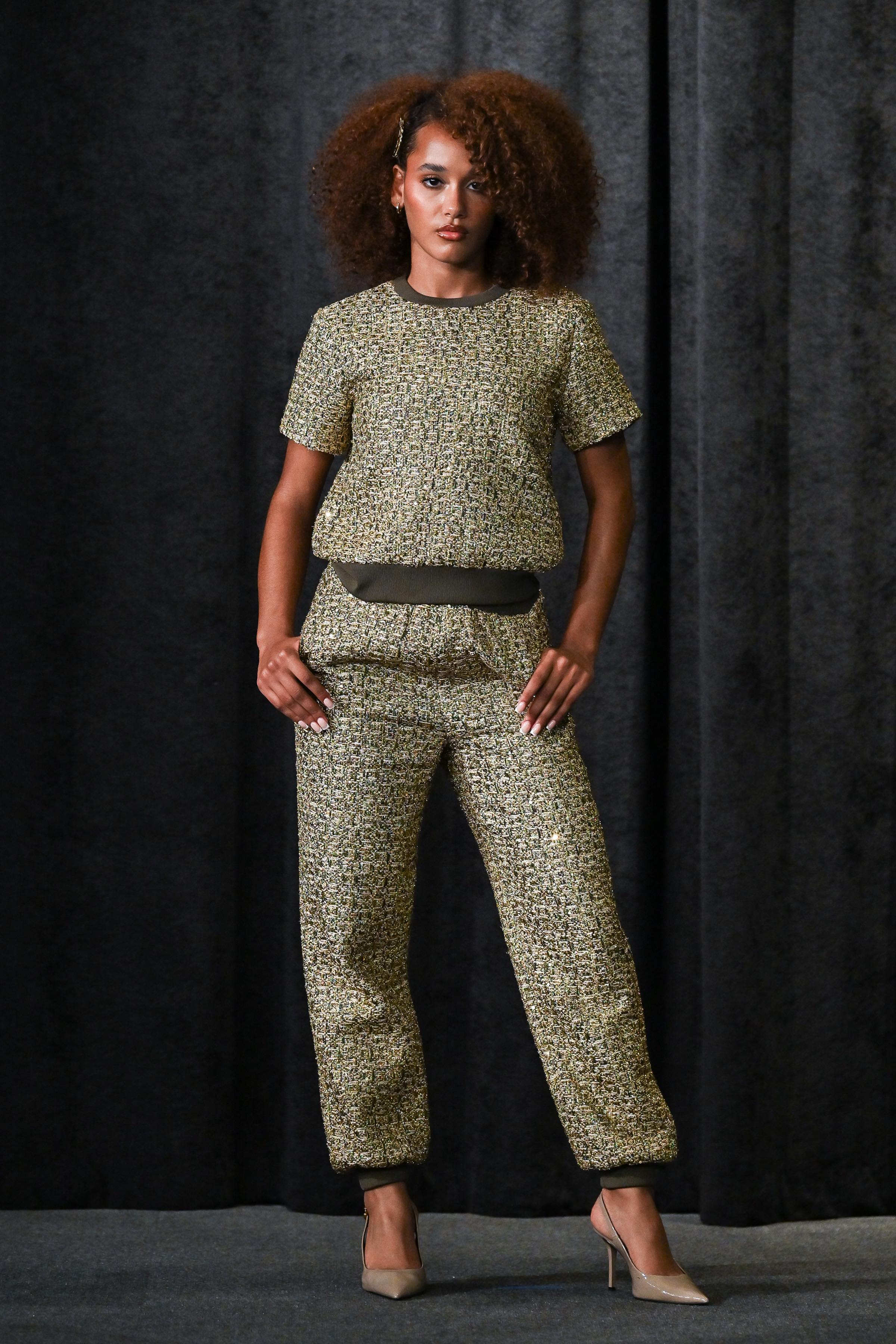 Model wearing a green patterned outfit against a dark background