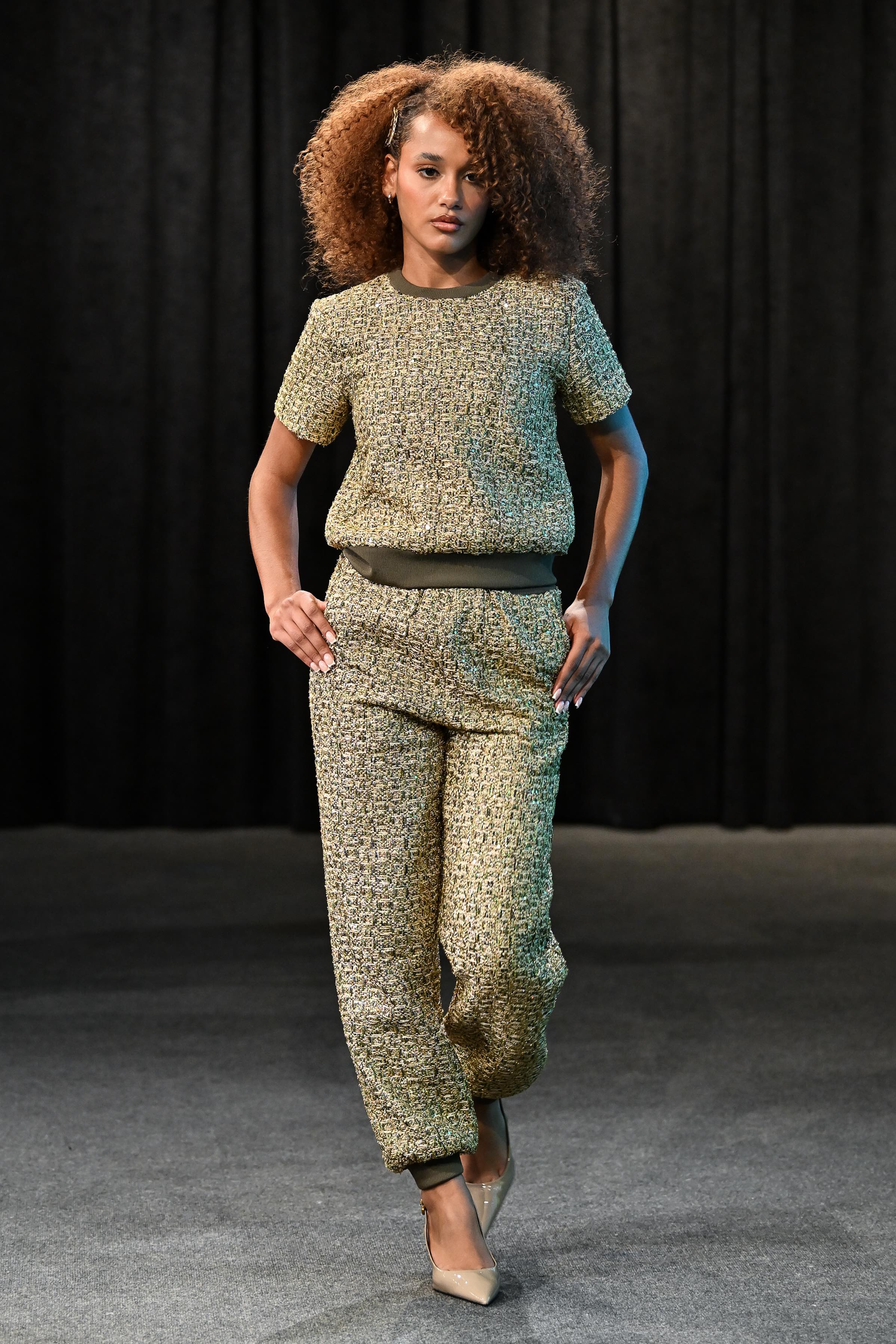 Model wearing a green patterned outfit against a dark background