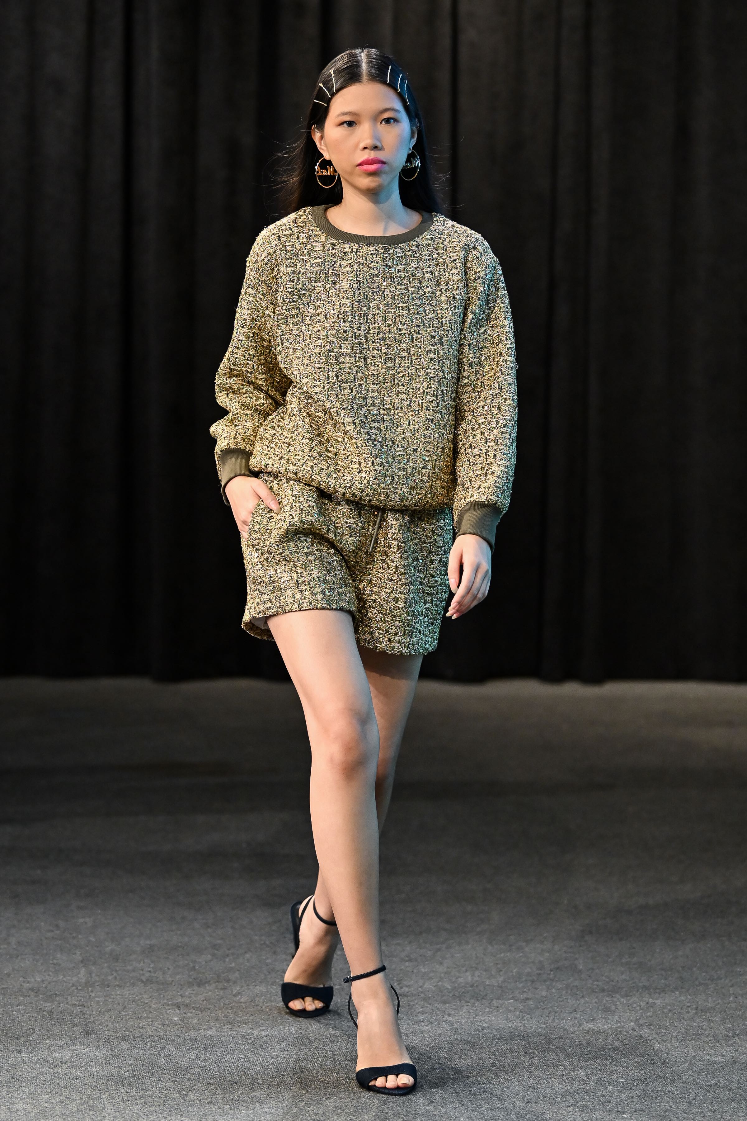 Person wearing a textured sweater and shorts set against a black background