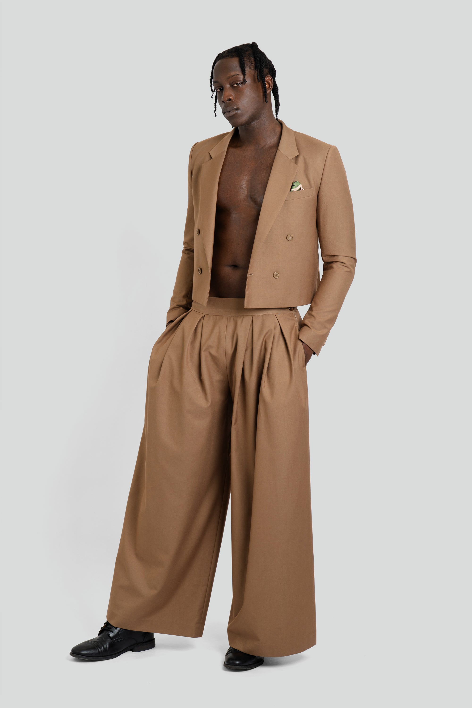 Man wearing a modern Maui X Lolita earth-toned brown suit featuring a cropped double-breasted blazer and pleated wide-leg pants