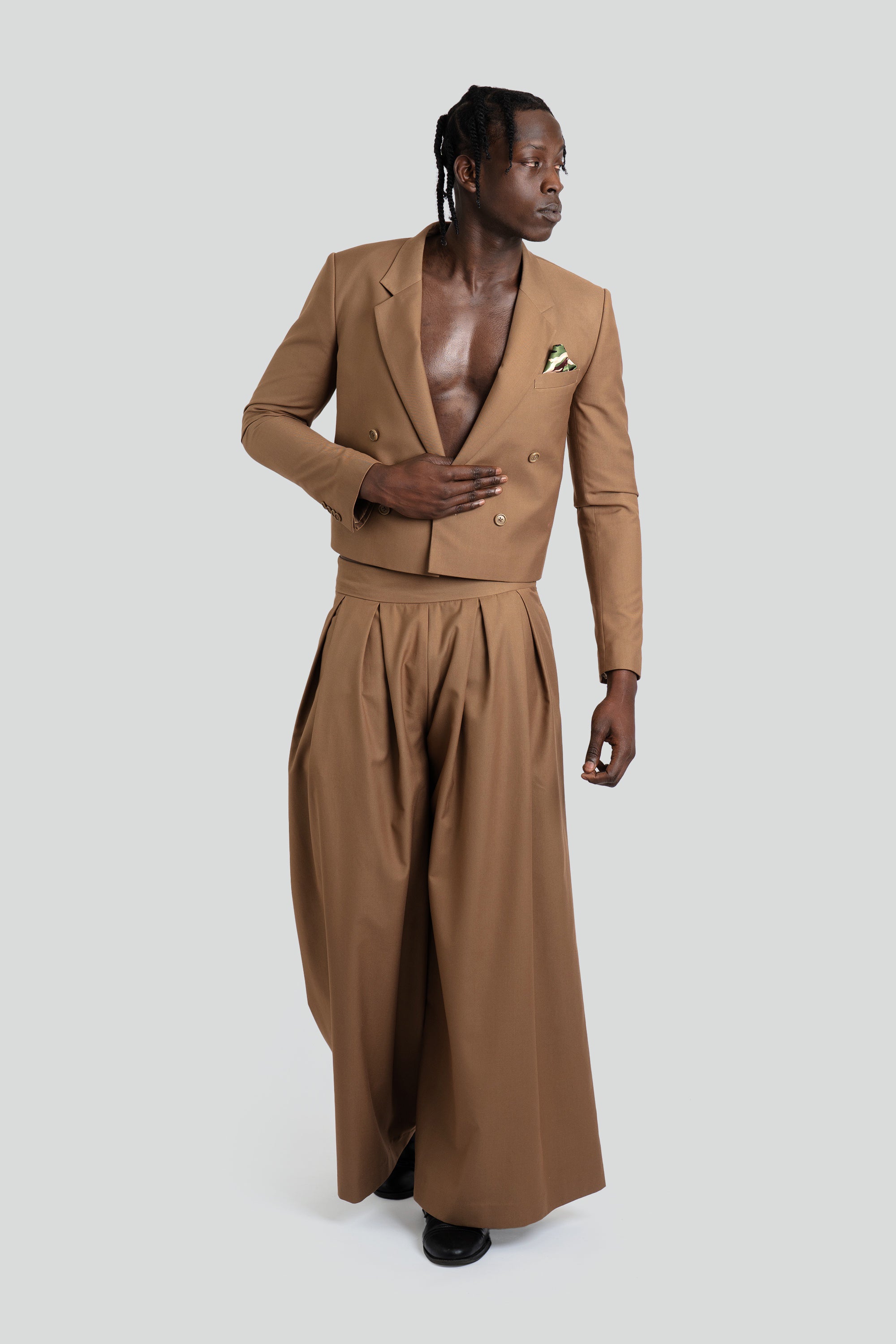Man wearing a brown suit with wide-leg pants on a white background