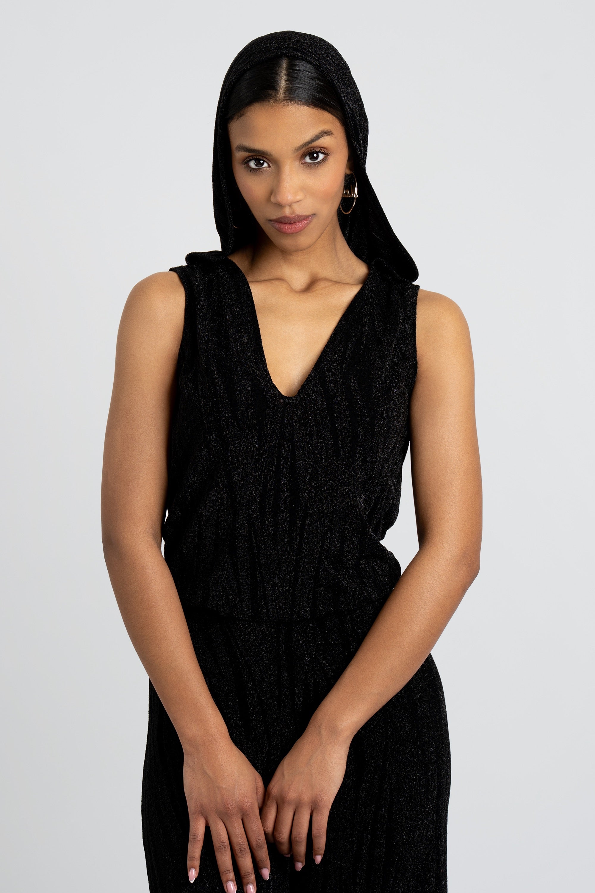 Close up of a woman wearing a black hooded jumpsuit on a white background