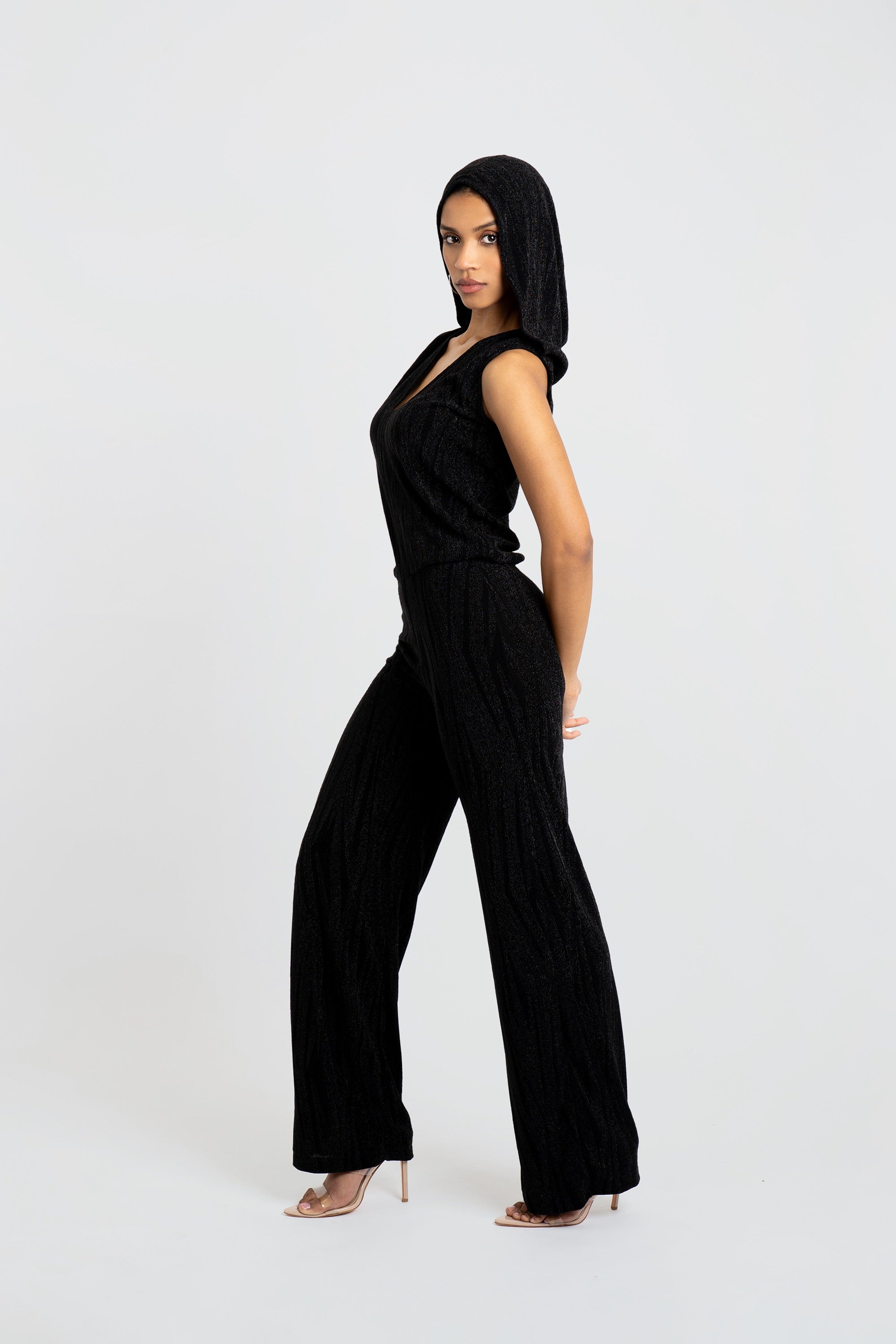 Woman wearing a black hooded jumpsuit on a white background