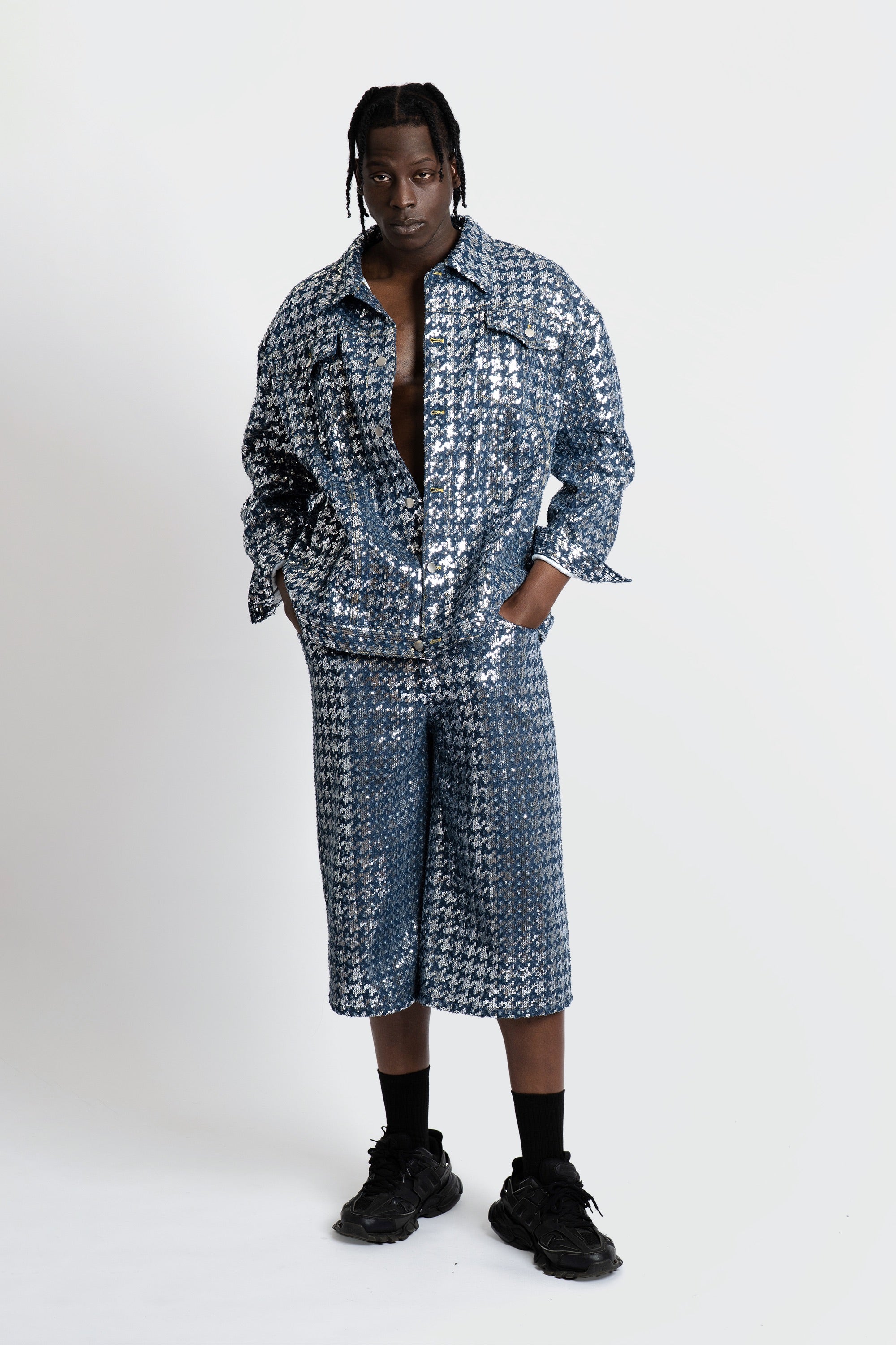 Man wearing a blue sequined denim set on a white background.