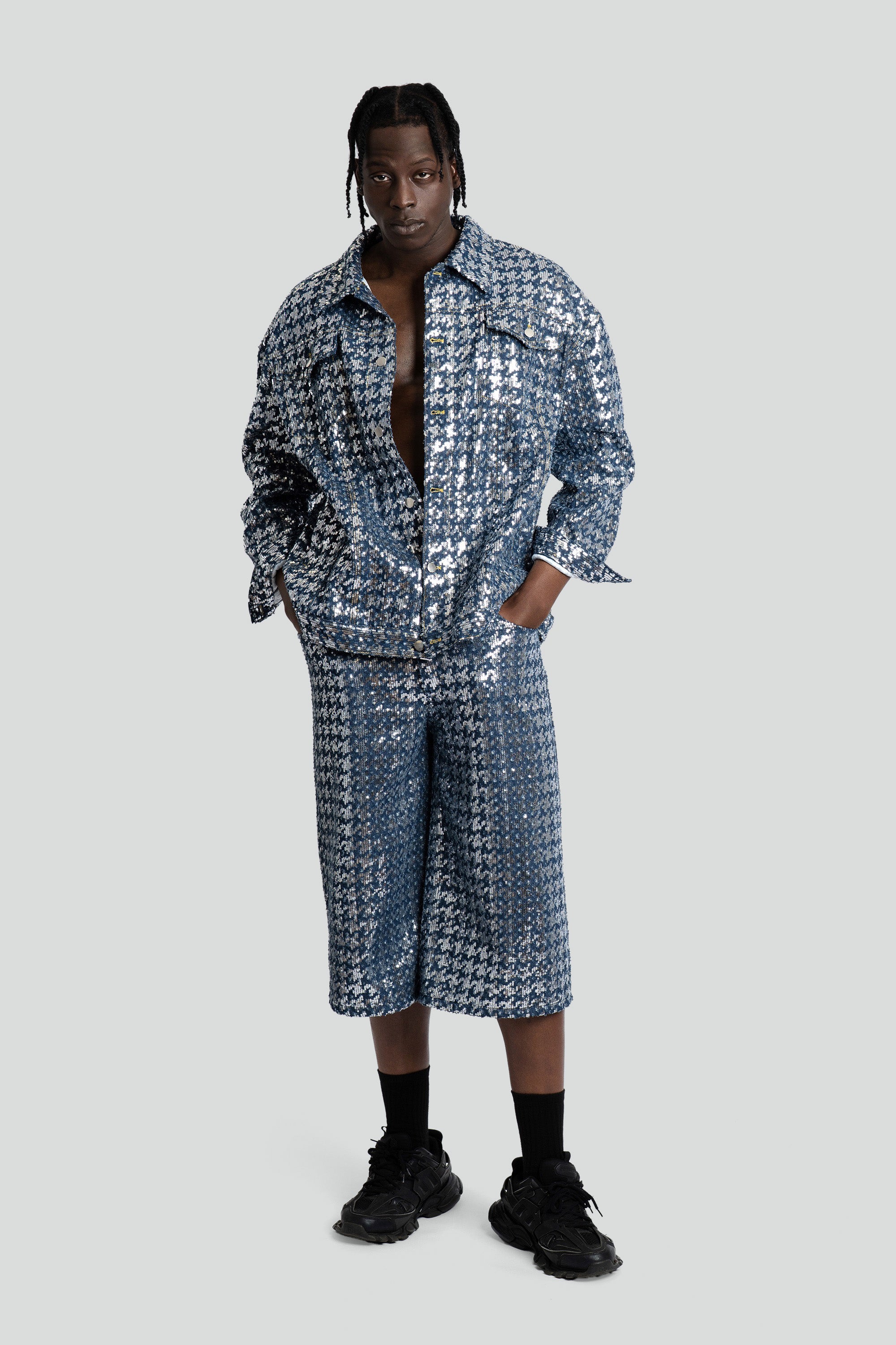 Man wearing a blue sequined denim set on a white background.