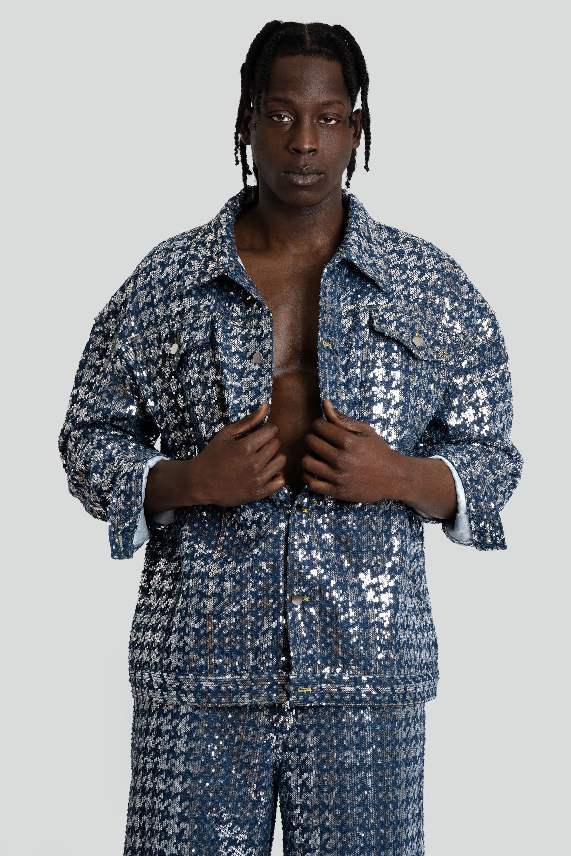 Man wearing a blue sequined denim set on a white background.