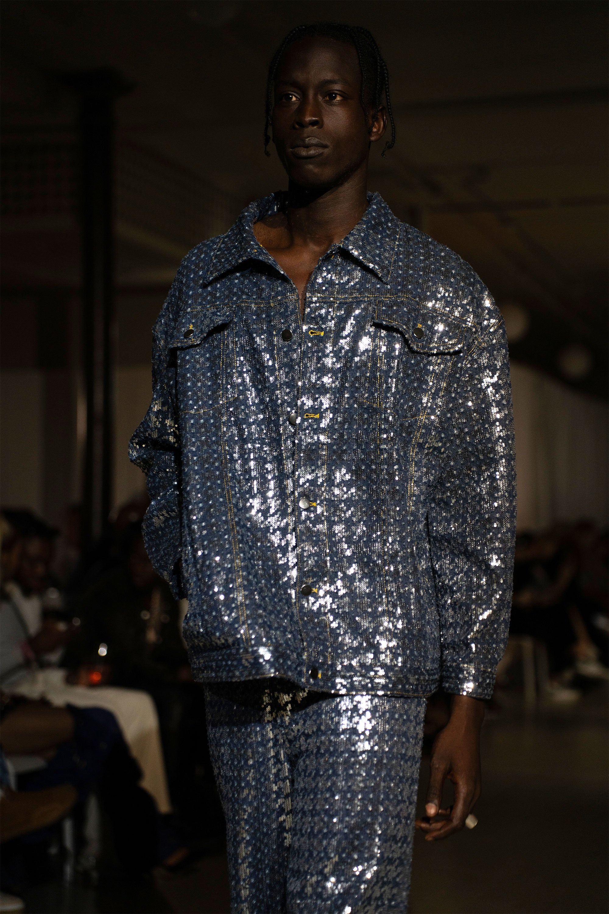 Model wearing a blue sequined denim set on the runway