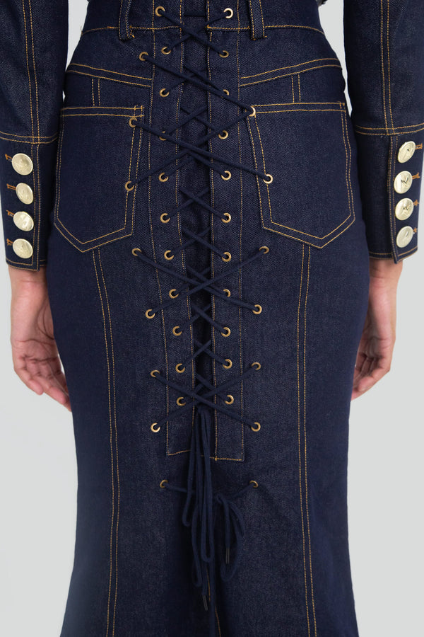 Close up view of a high waisted dark indigo denim pencil skirt highlighting the sharp contrast topstitching and premium woven fabric texture
