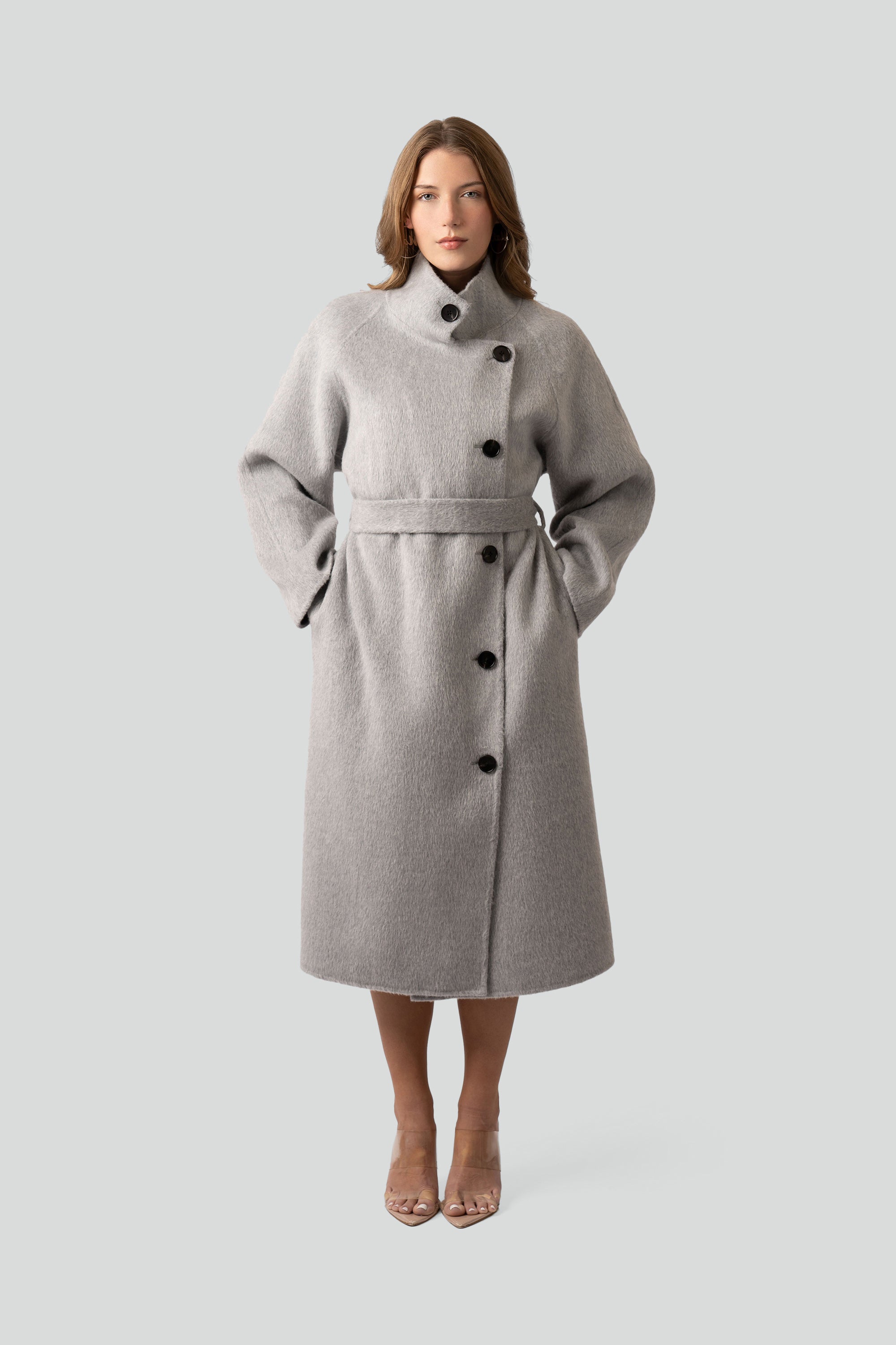 Woman wearing a gray wool coat with buttons and belt on a white background