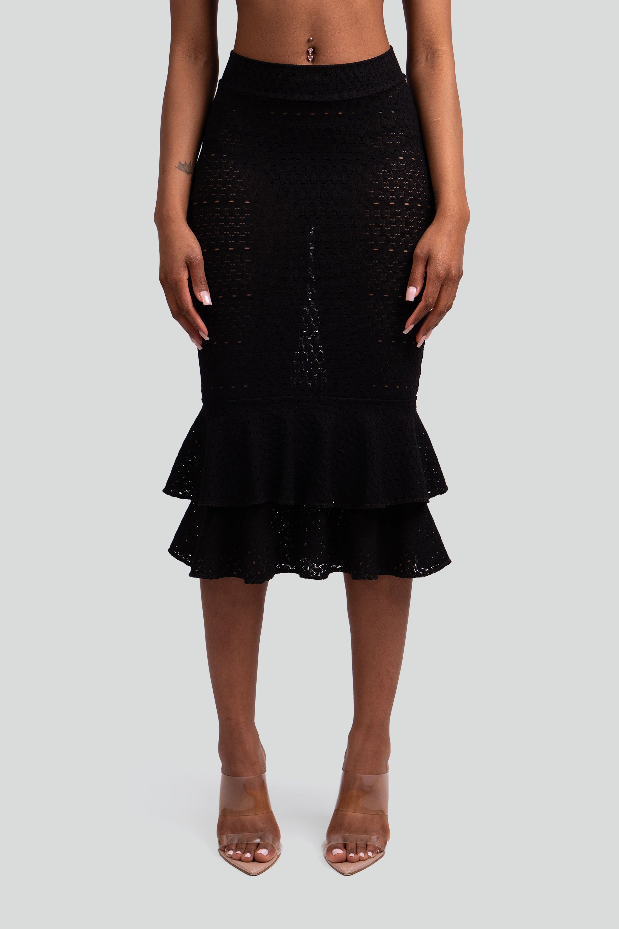 Close up of a woman wearing a black lace ruffled skirt on a white background