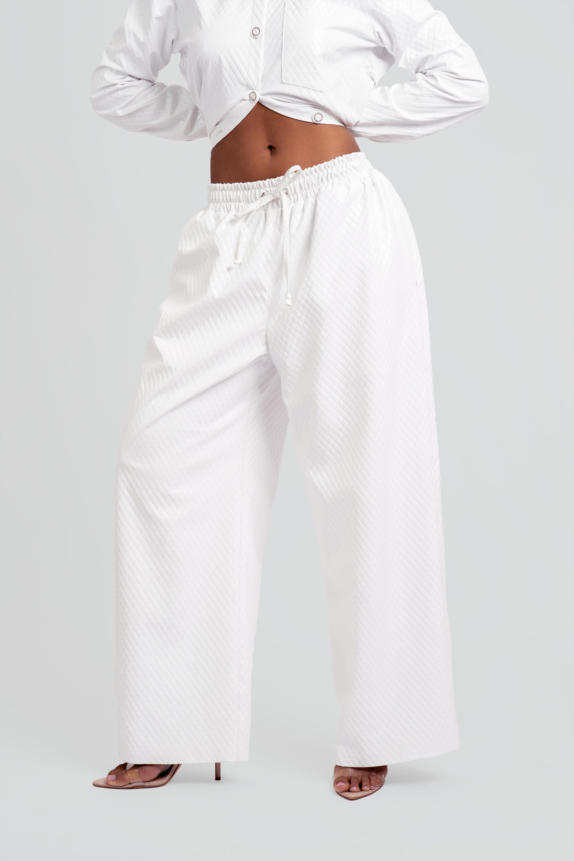 Person wearing a white shirt and wide-leg pants on a plain background