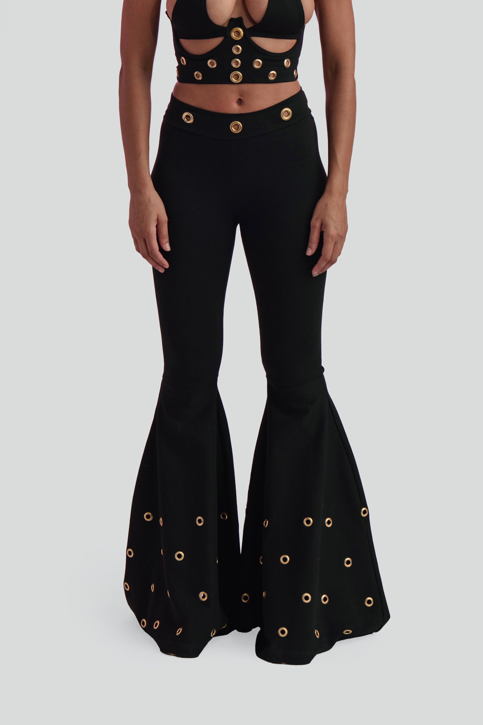 Black bell-bottom pants with gold embellishments on a gray background