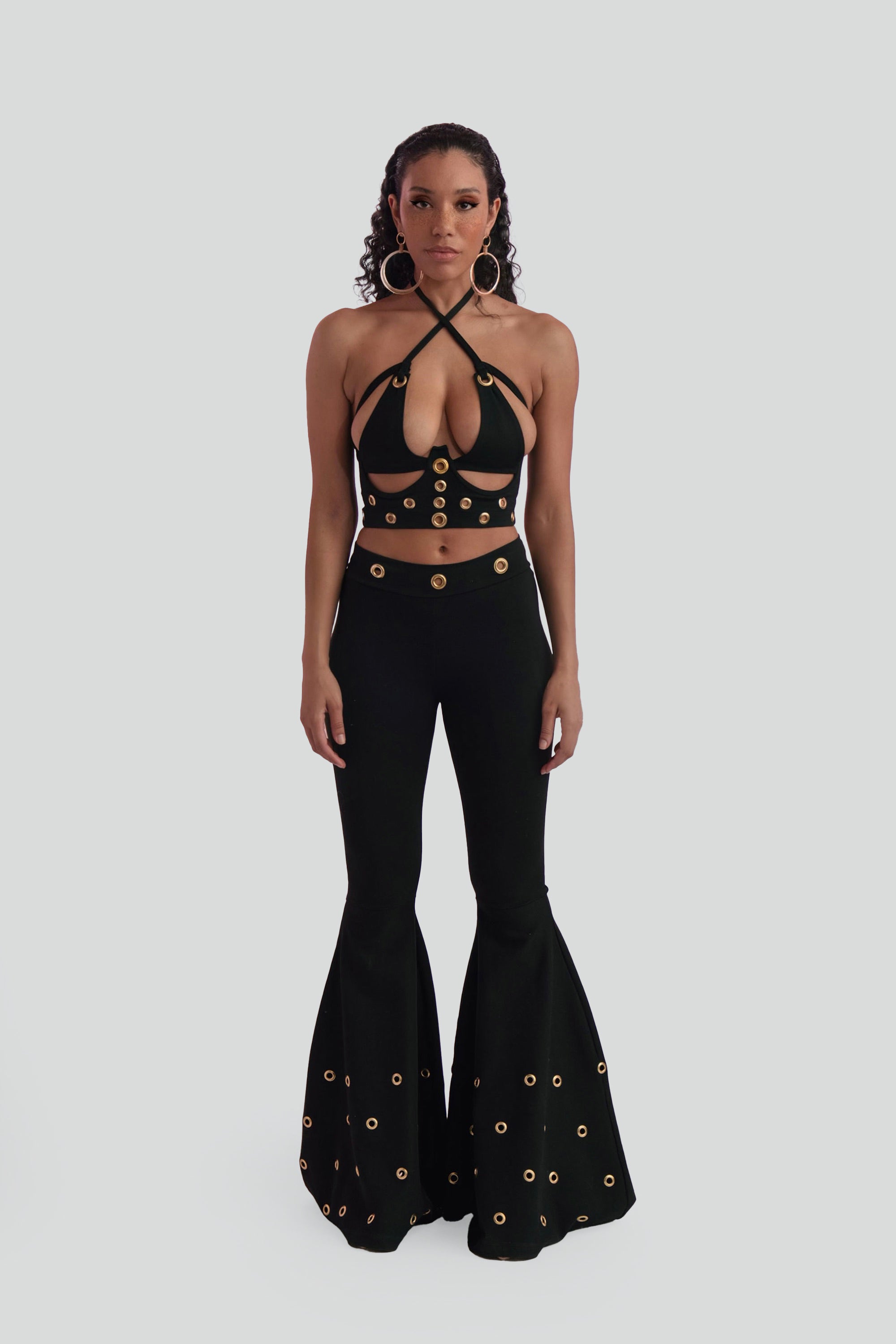 Woman wearing a black outfit with gold embellishments on a white background