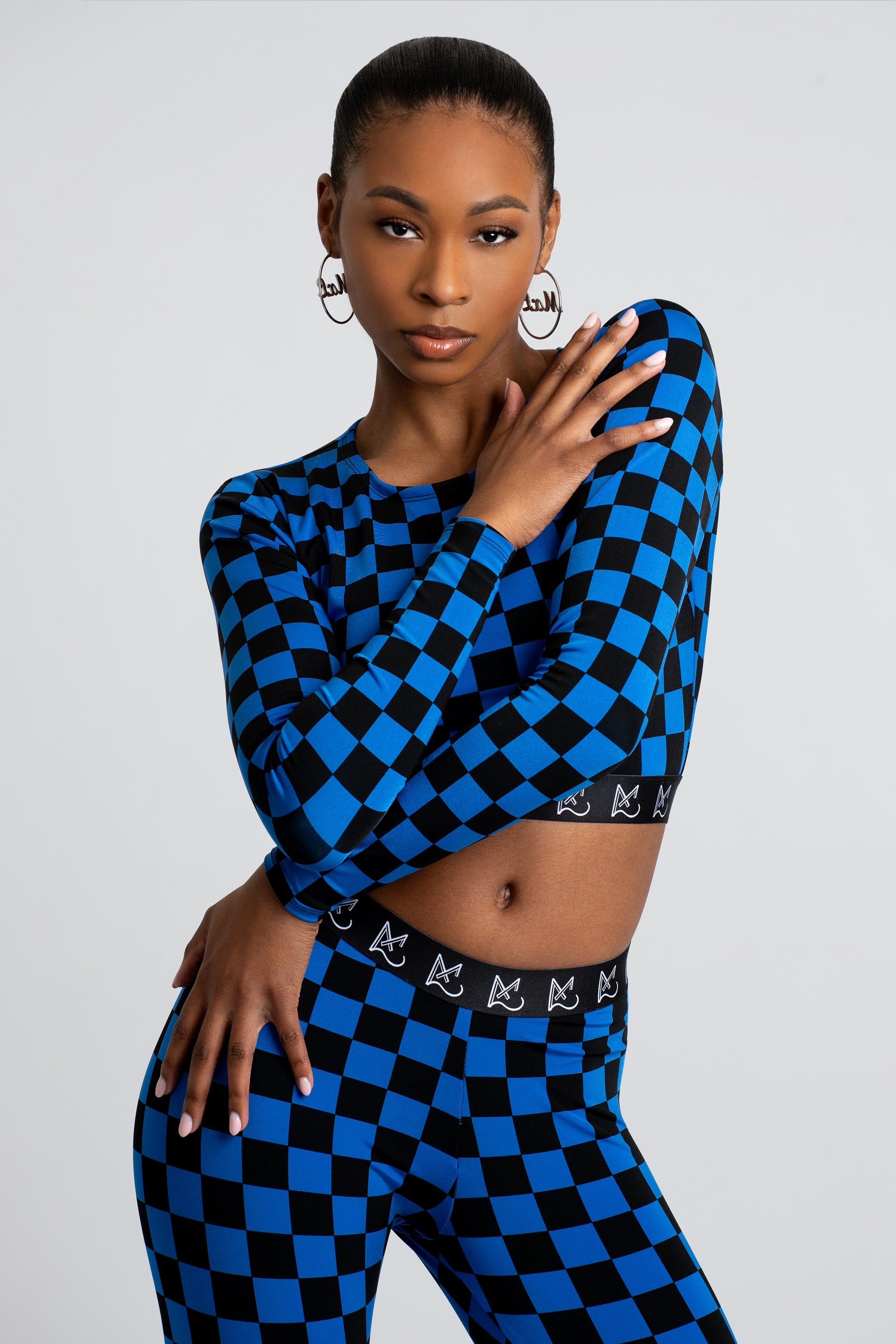 Woman wearing a blue and black checkered crop top and leggings on a white background