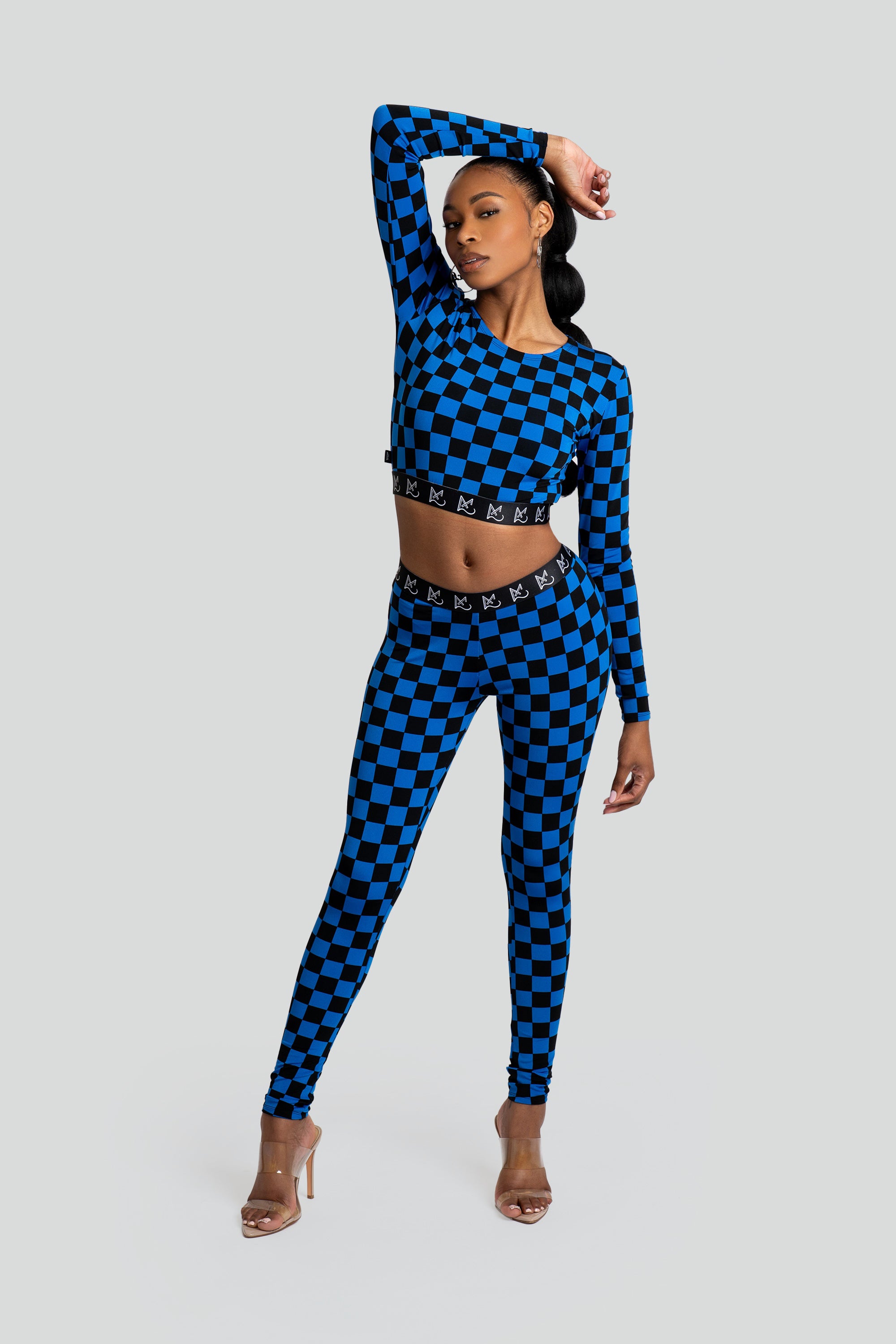Woman wearing a blue and black checkered crop top and leggings on a white background