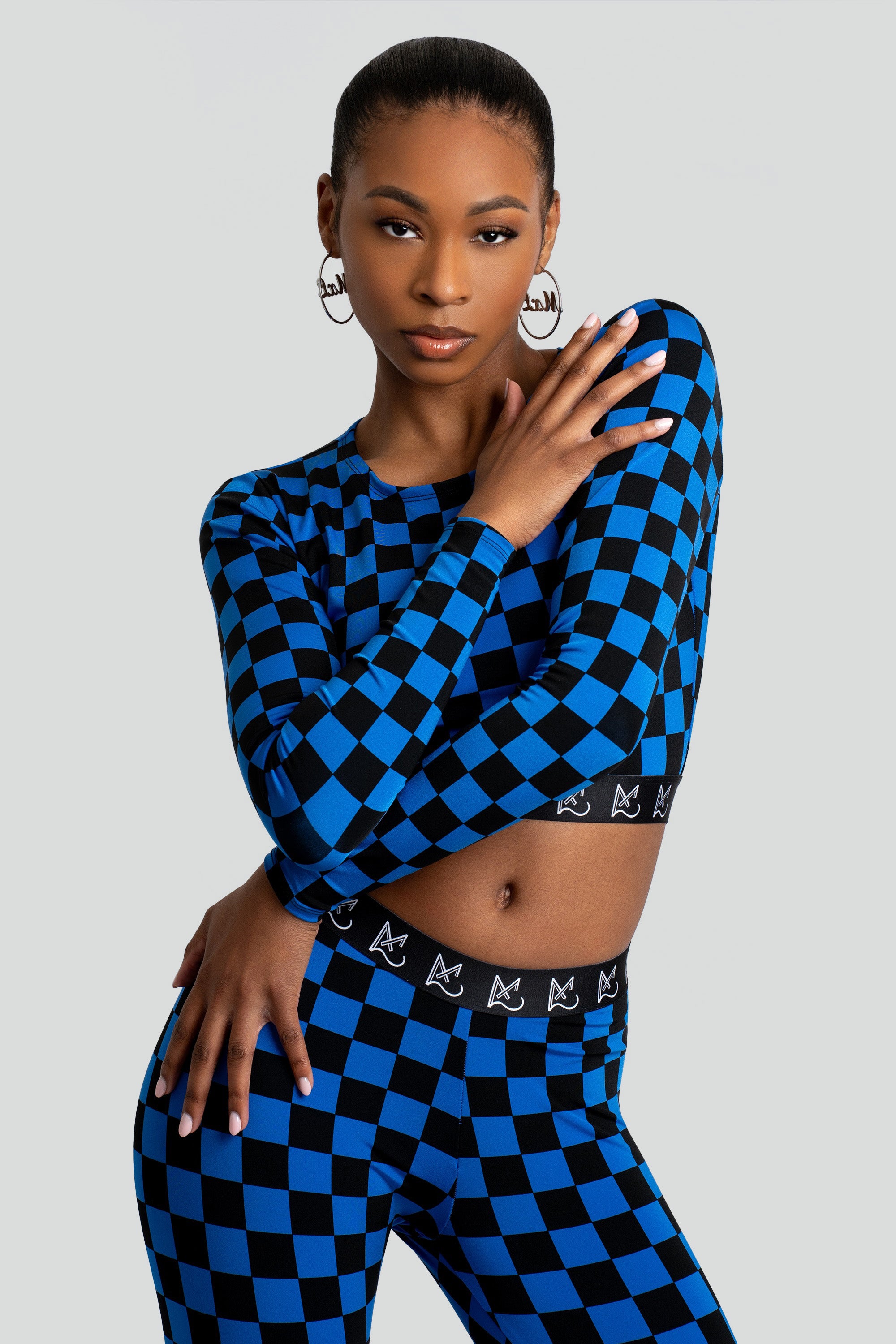 Woman wearing a blue and black checkered crop top and leggings on a white background