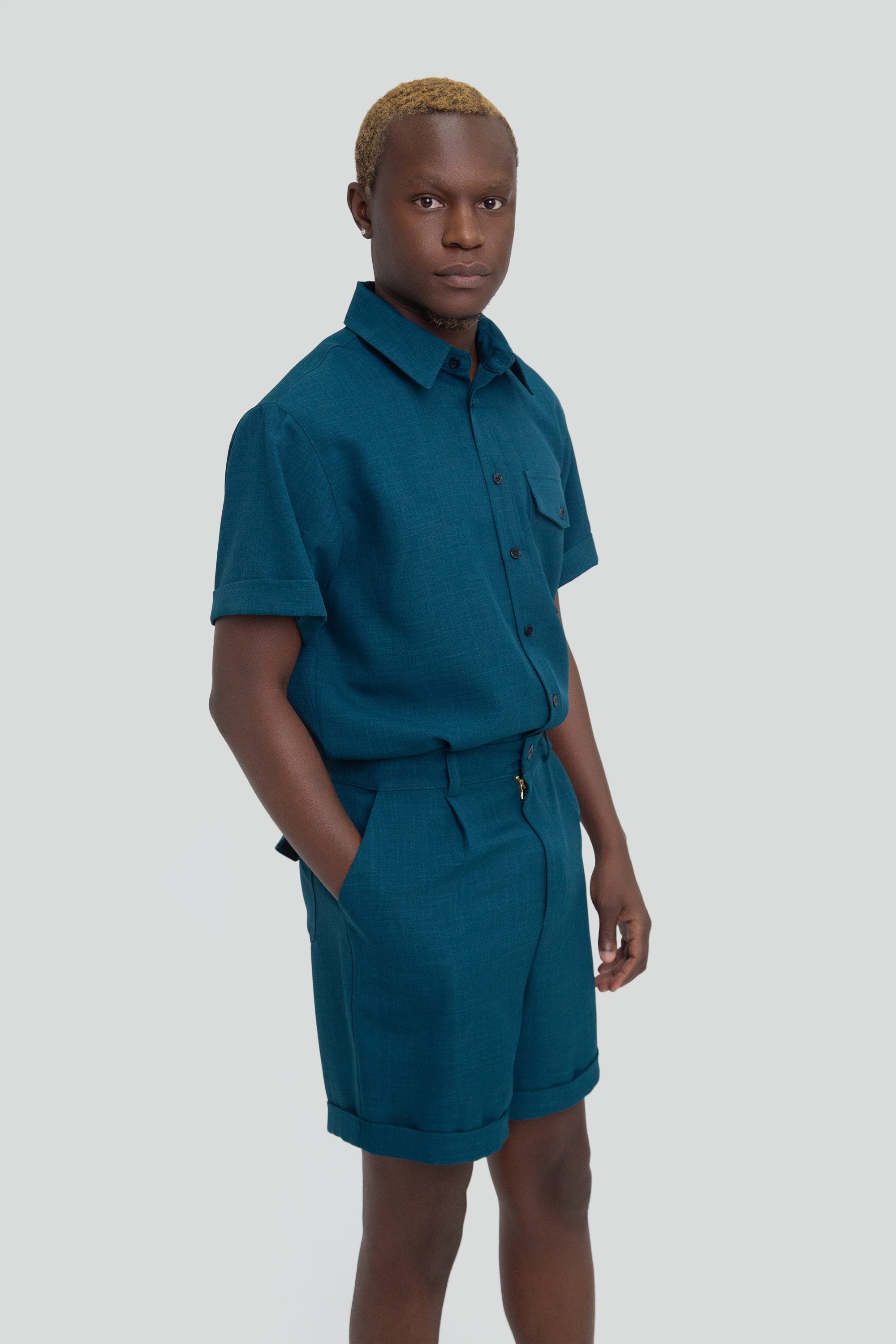 Person wearing a dark teal shirt and shorts set on a plain background