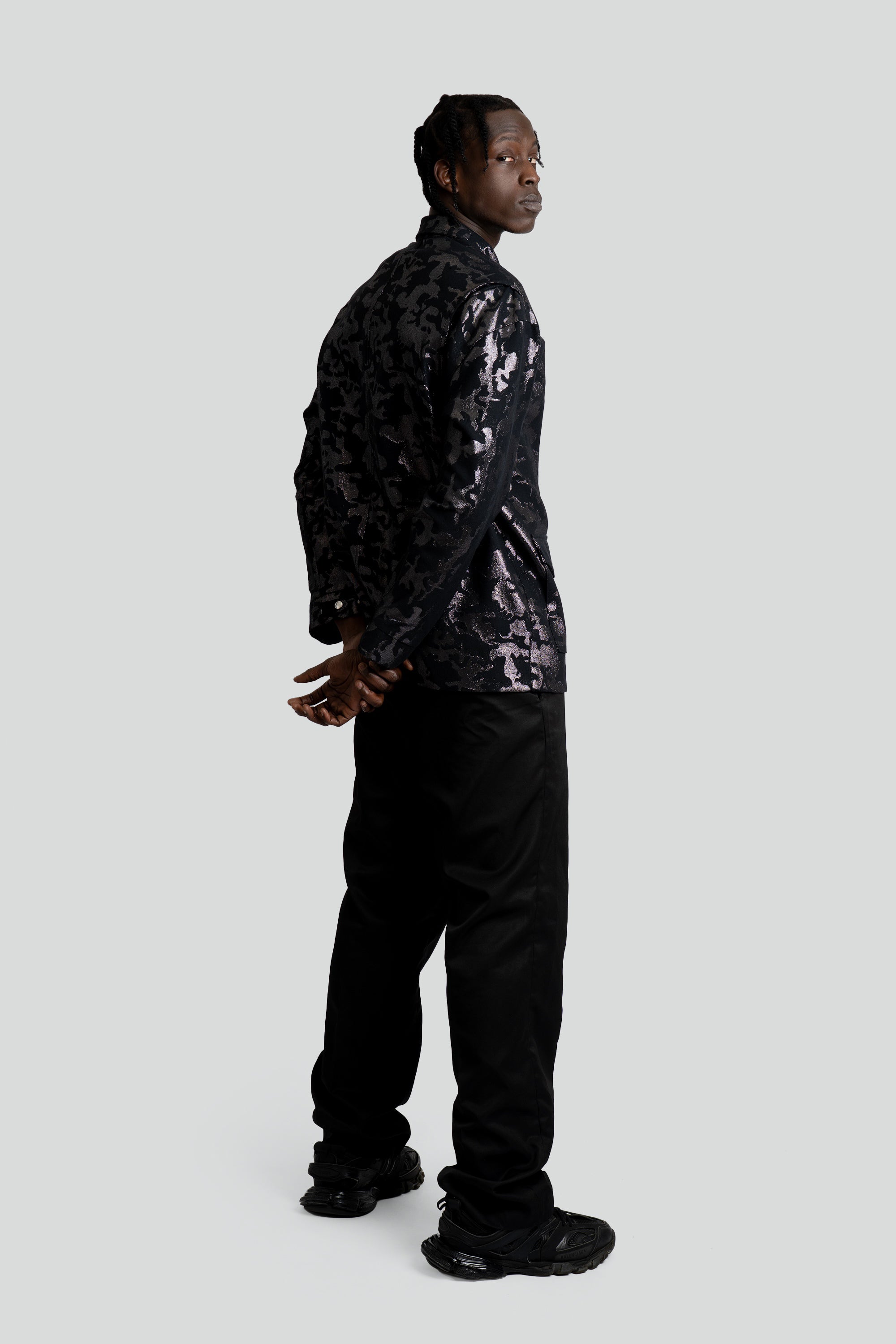 Person wearing a black sequin jacket and black pants on a white background