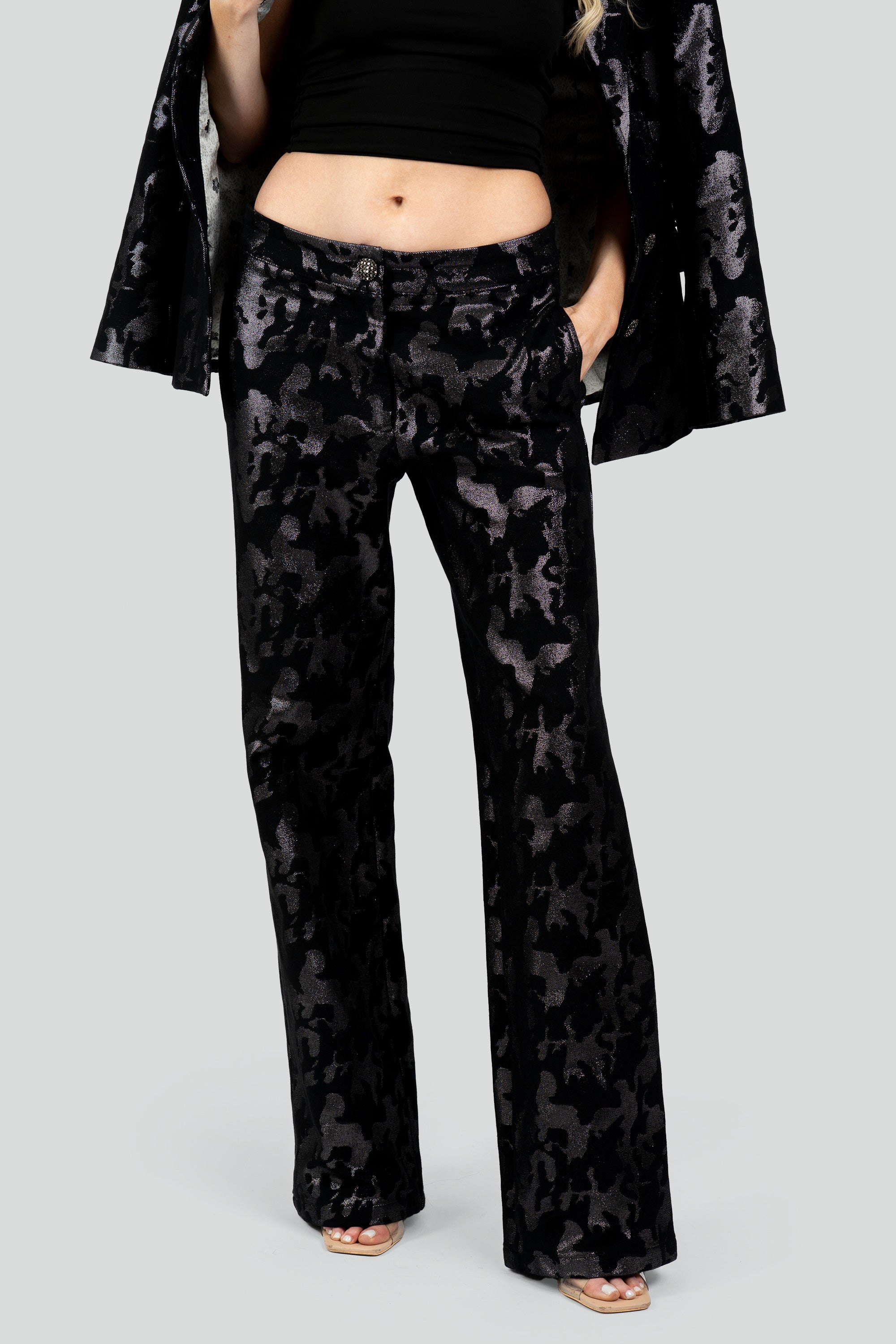 Close up view of a woman wearing black camo suit pants on a white background