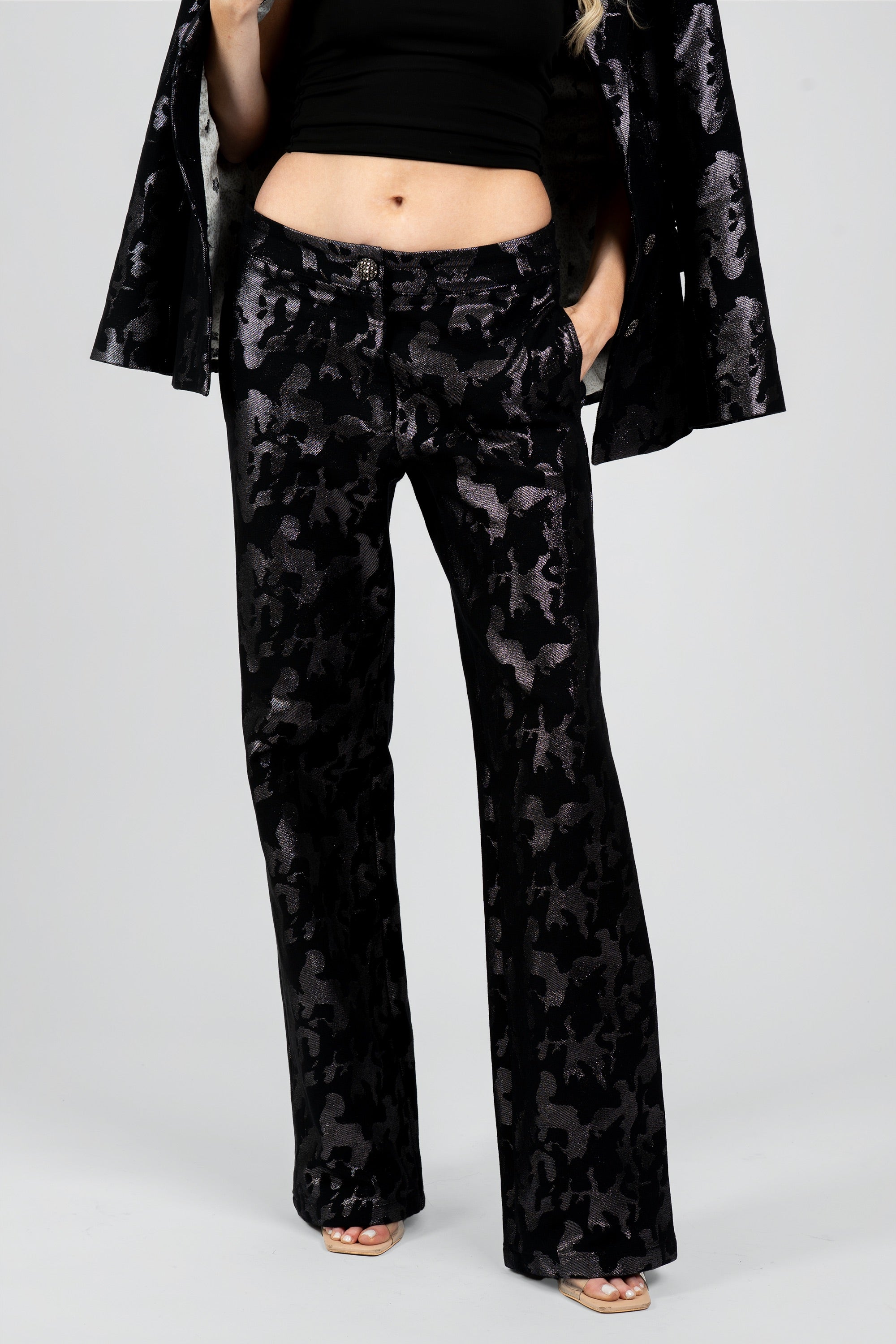 Close up view of a woman wearing black camo suit pants on a white background