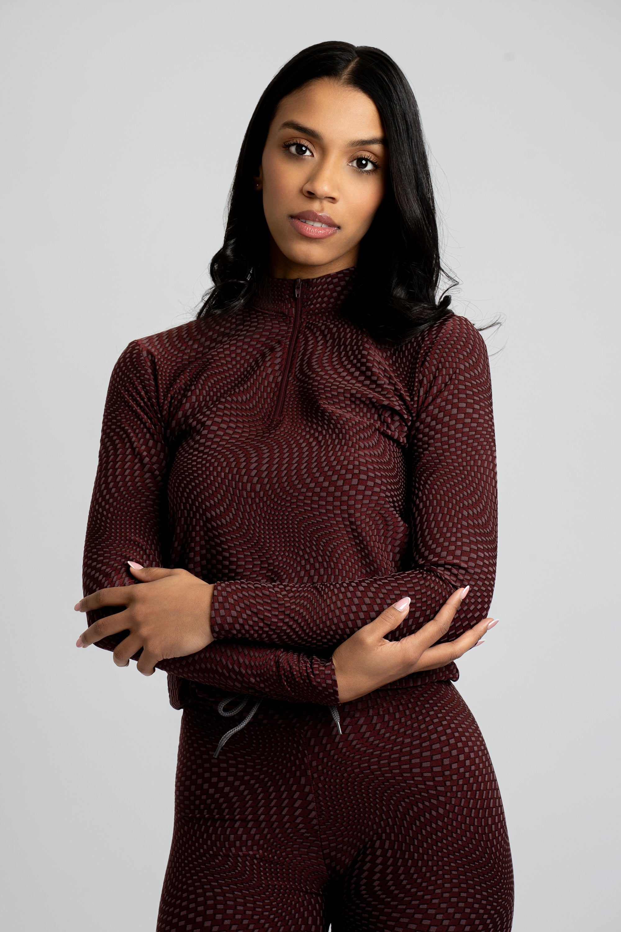 Model wearing a maroon patterned workout set on a white background