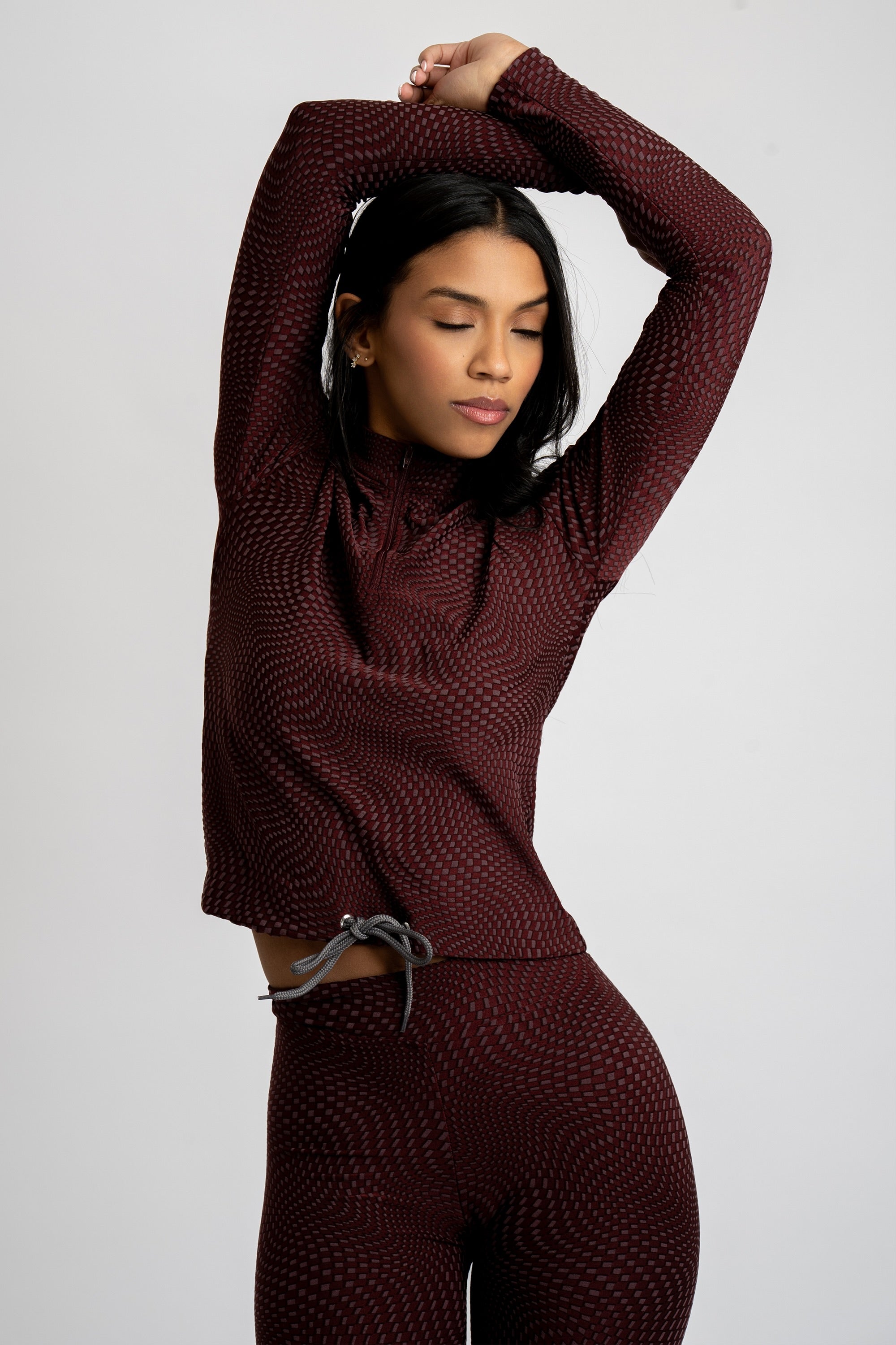 Model wearing a maroon patterned workout set on a white background