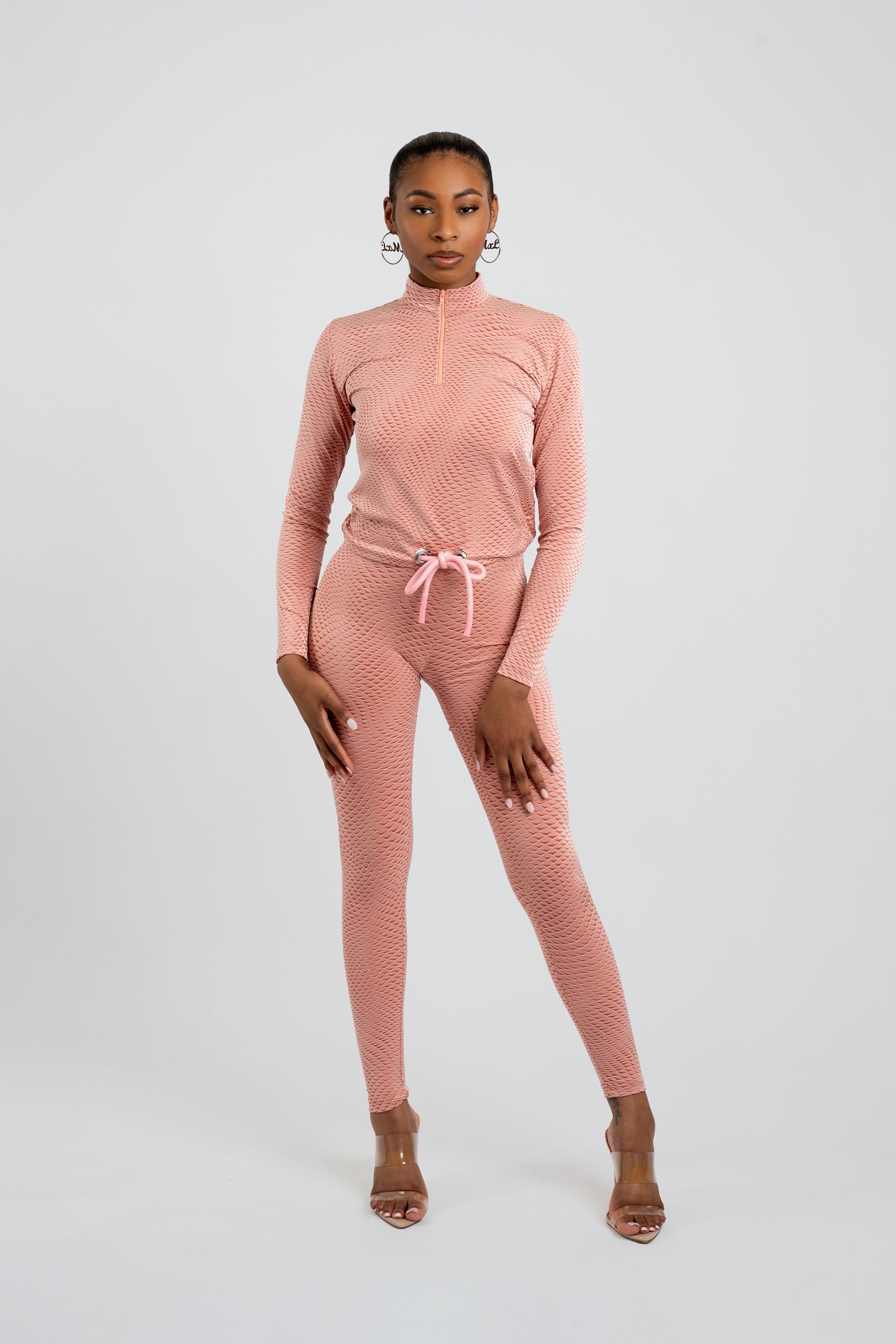 Model wearing a pink patterned workout set on a white background