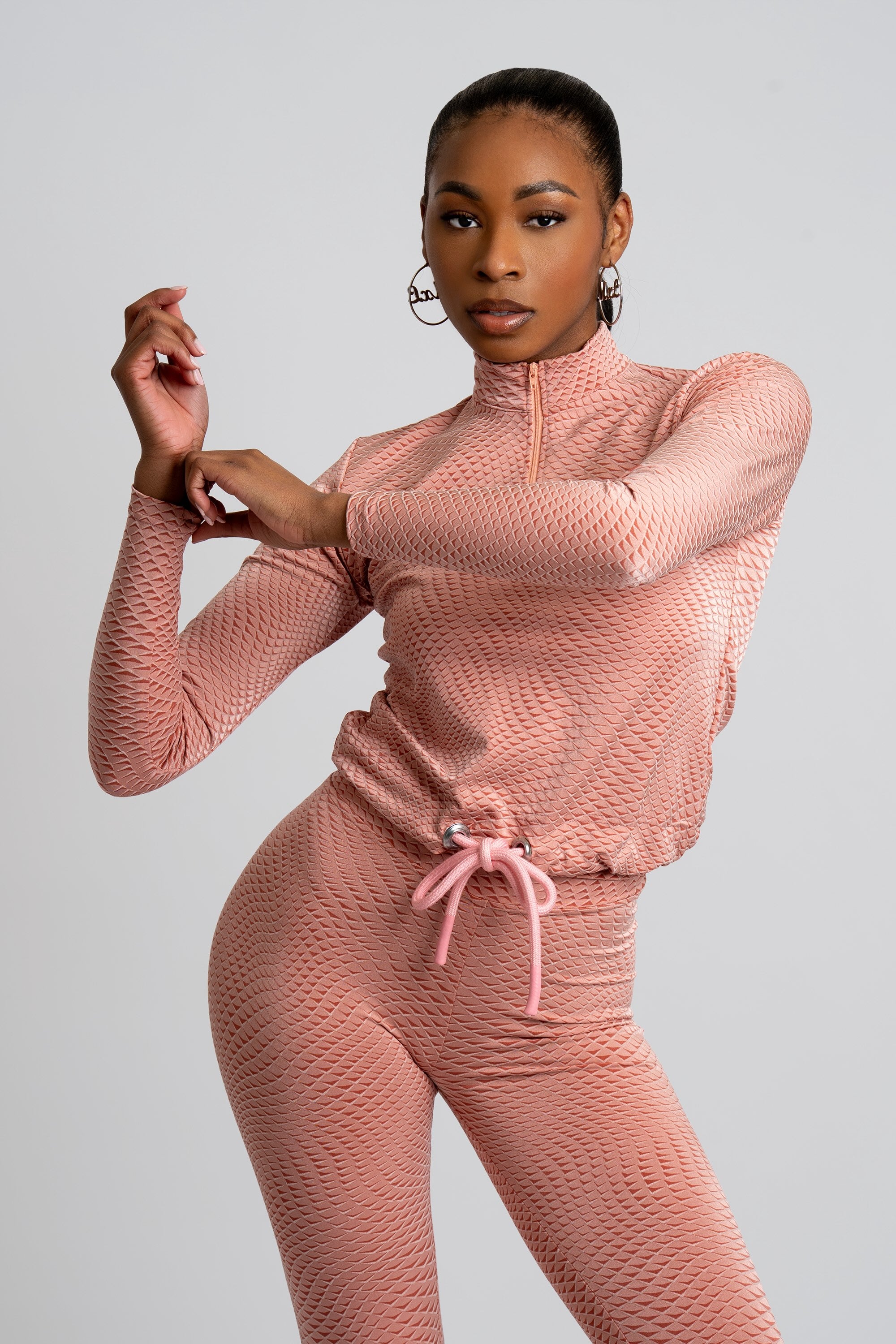 Model wearing a pink patterned workout set on a white background