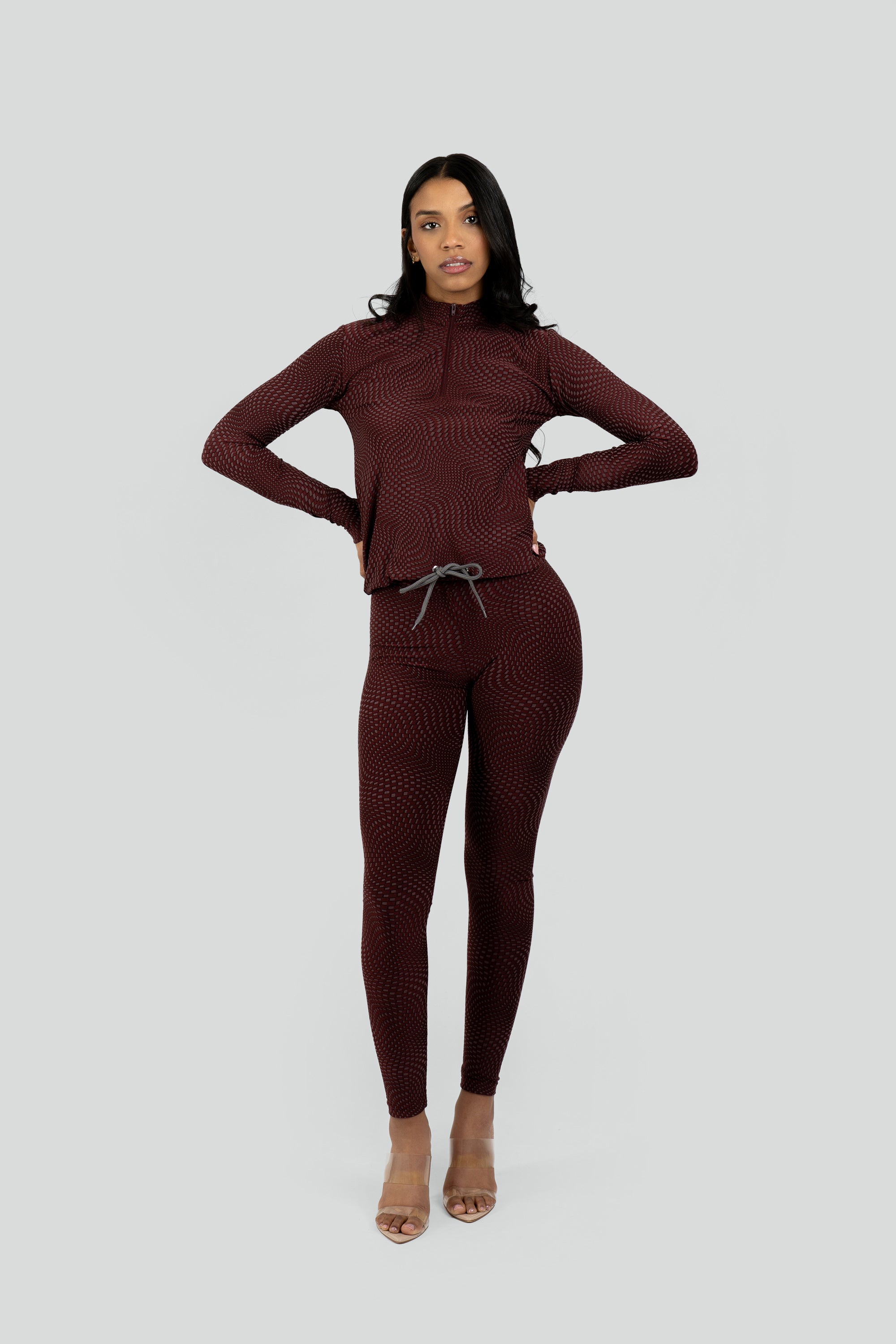 Model wearing a maroon patterned workout set on a white background