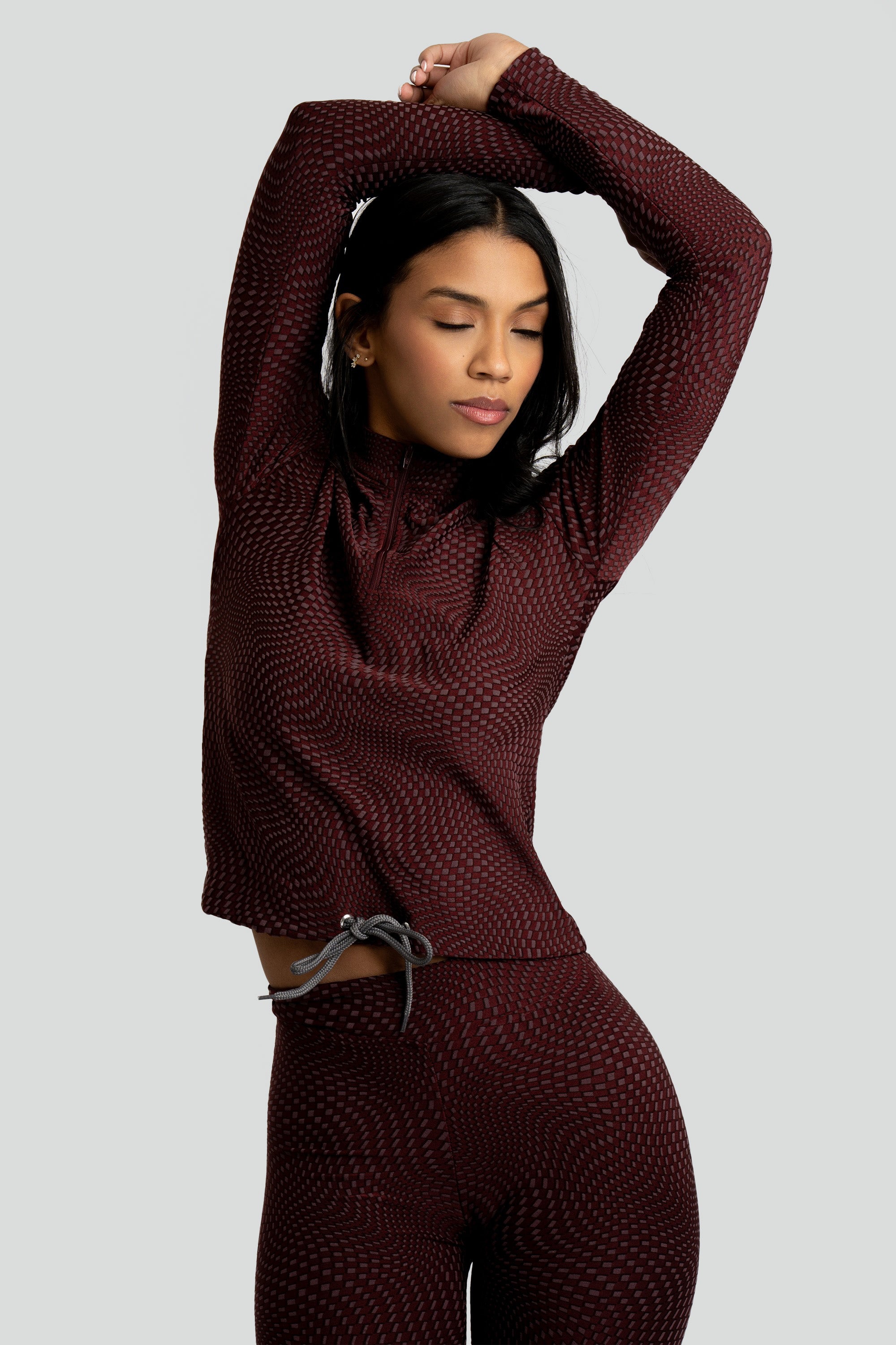 Model wearing a maroon patterned workout set on a white background