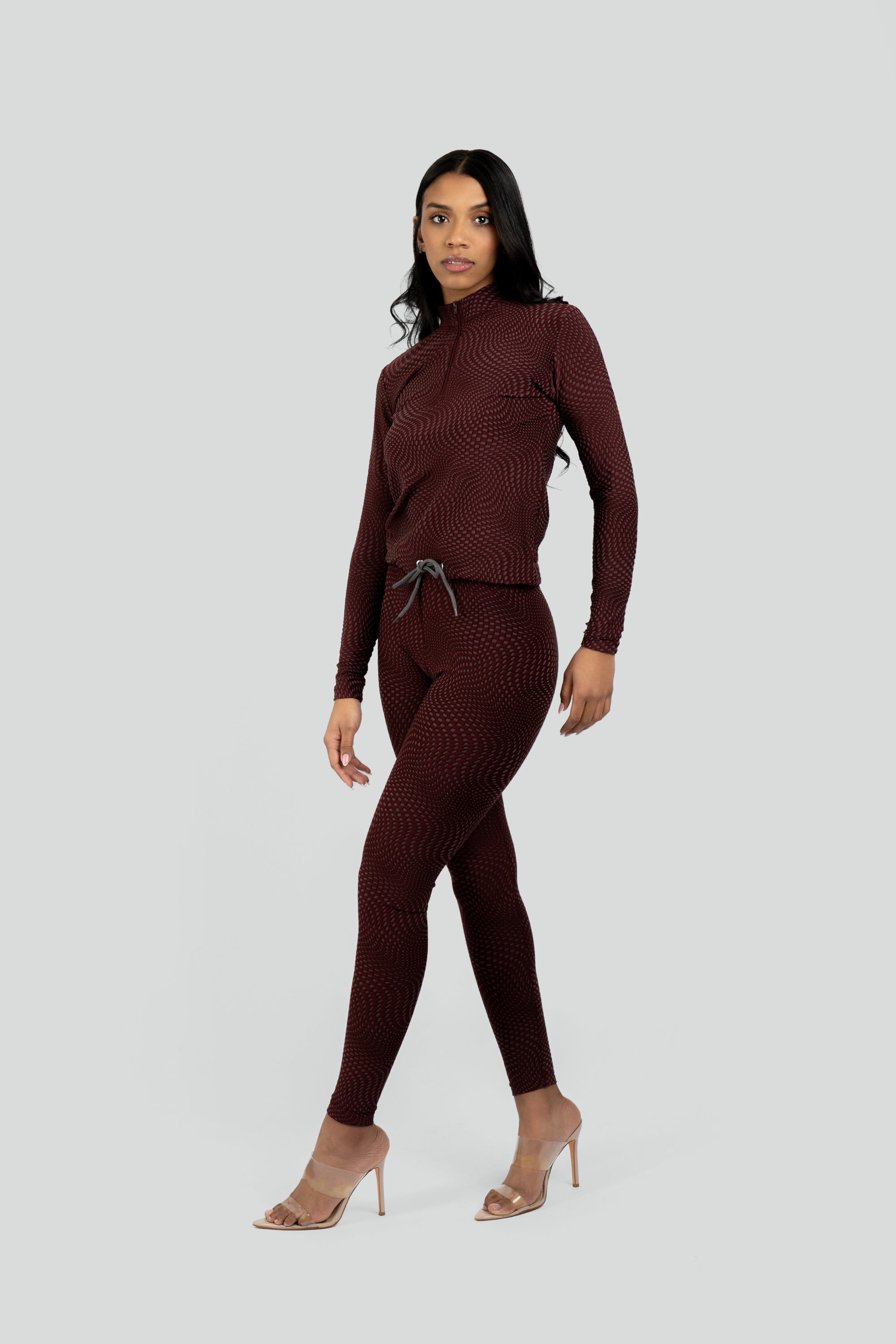 Model wearing a maroon patterned workout set on a white background