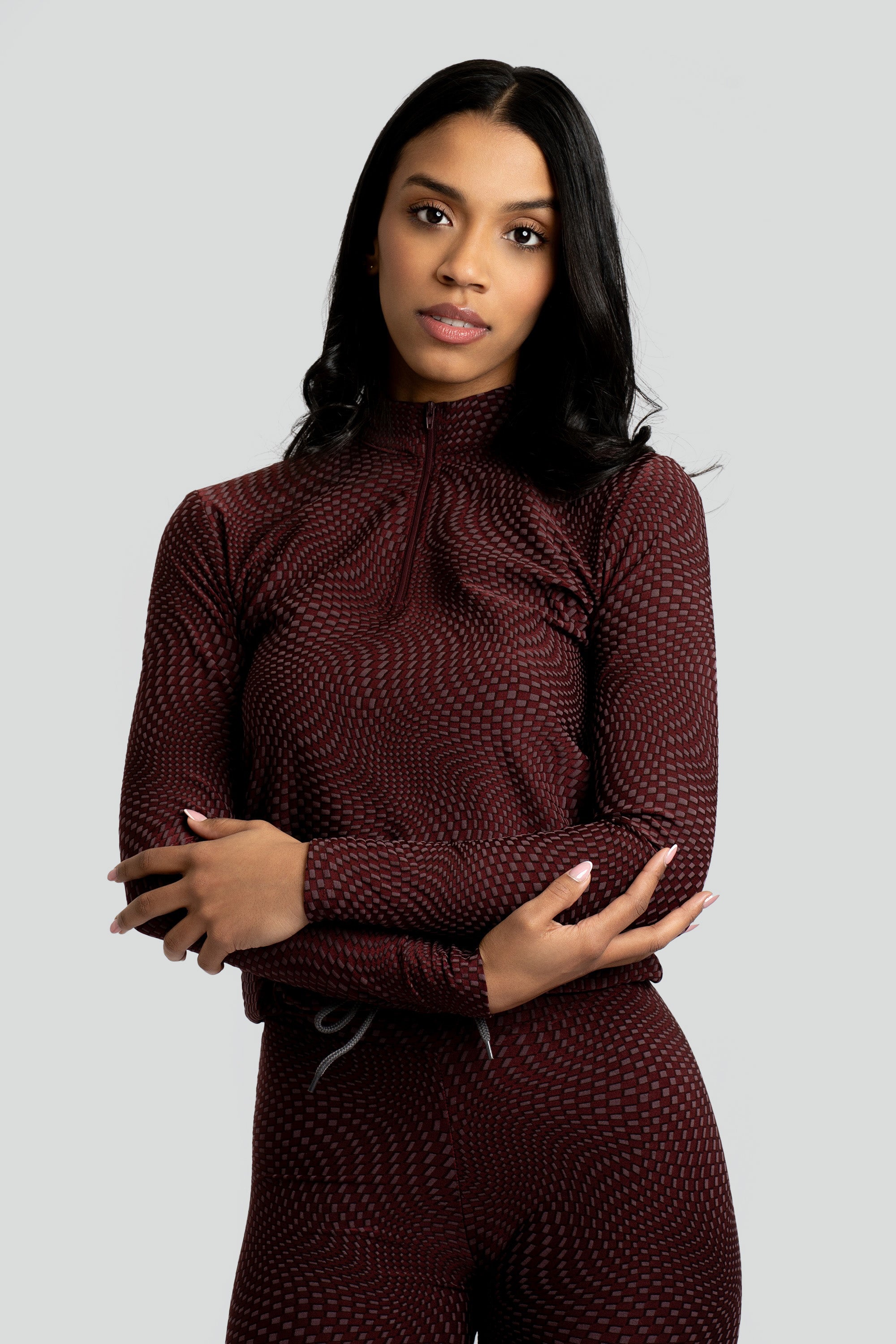 Model wearing a maroon patterned workout set on a white background