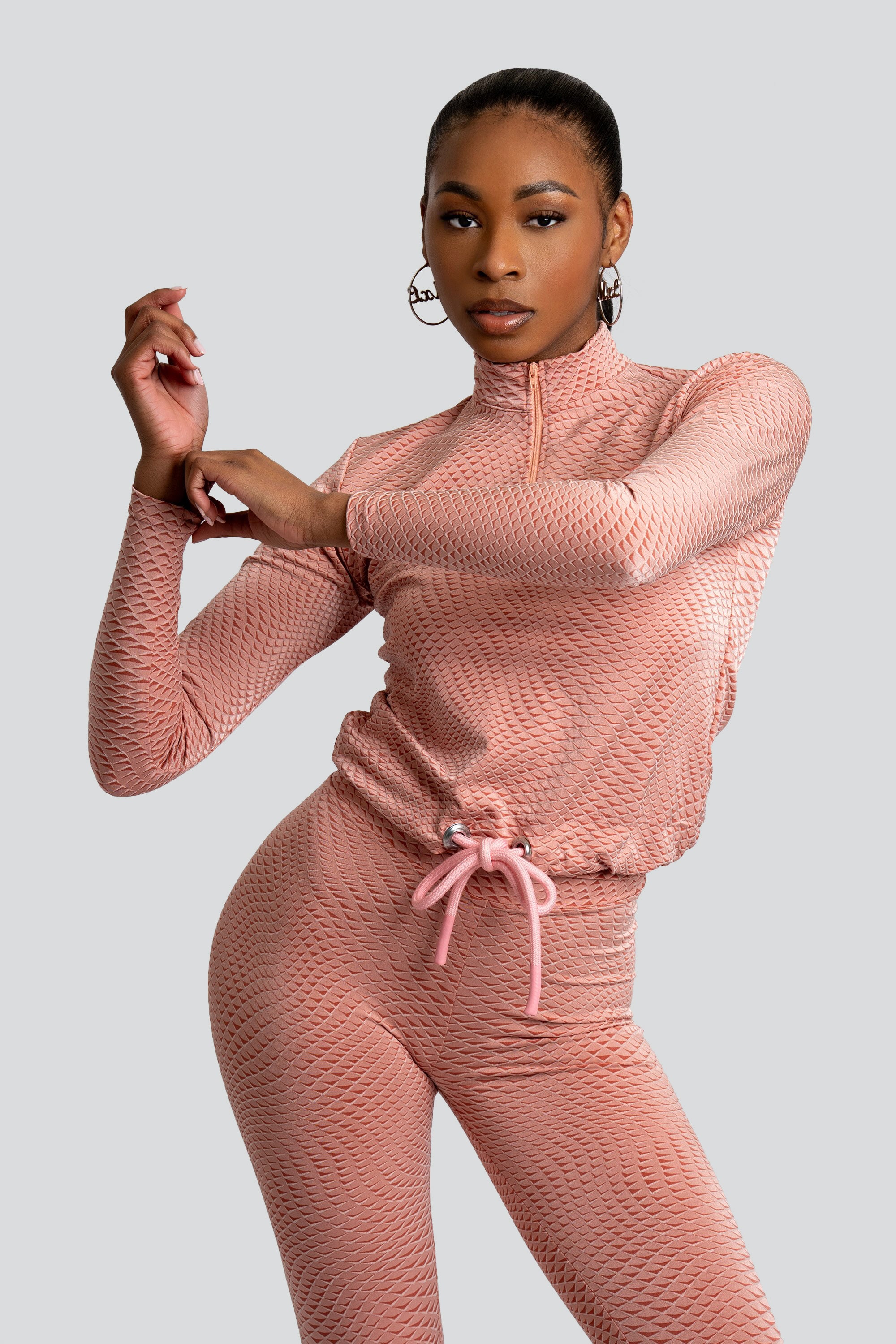 Model wearing a pink patterned workout set on a white background