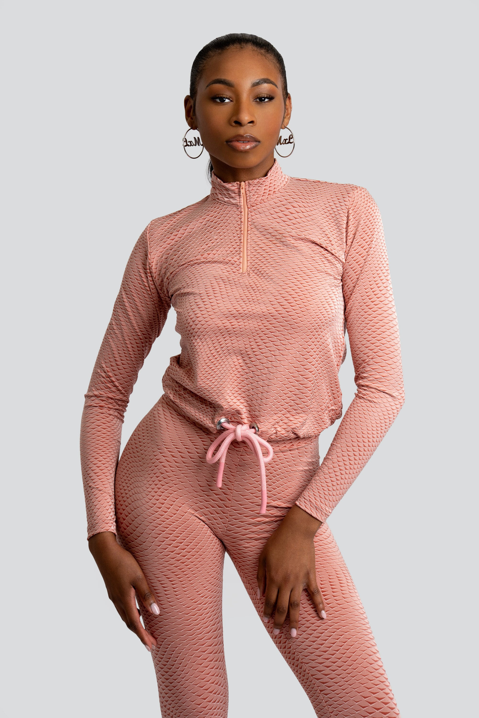 Model wearing a pink patterned workout set on a white background