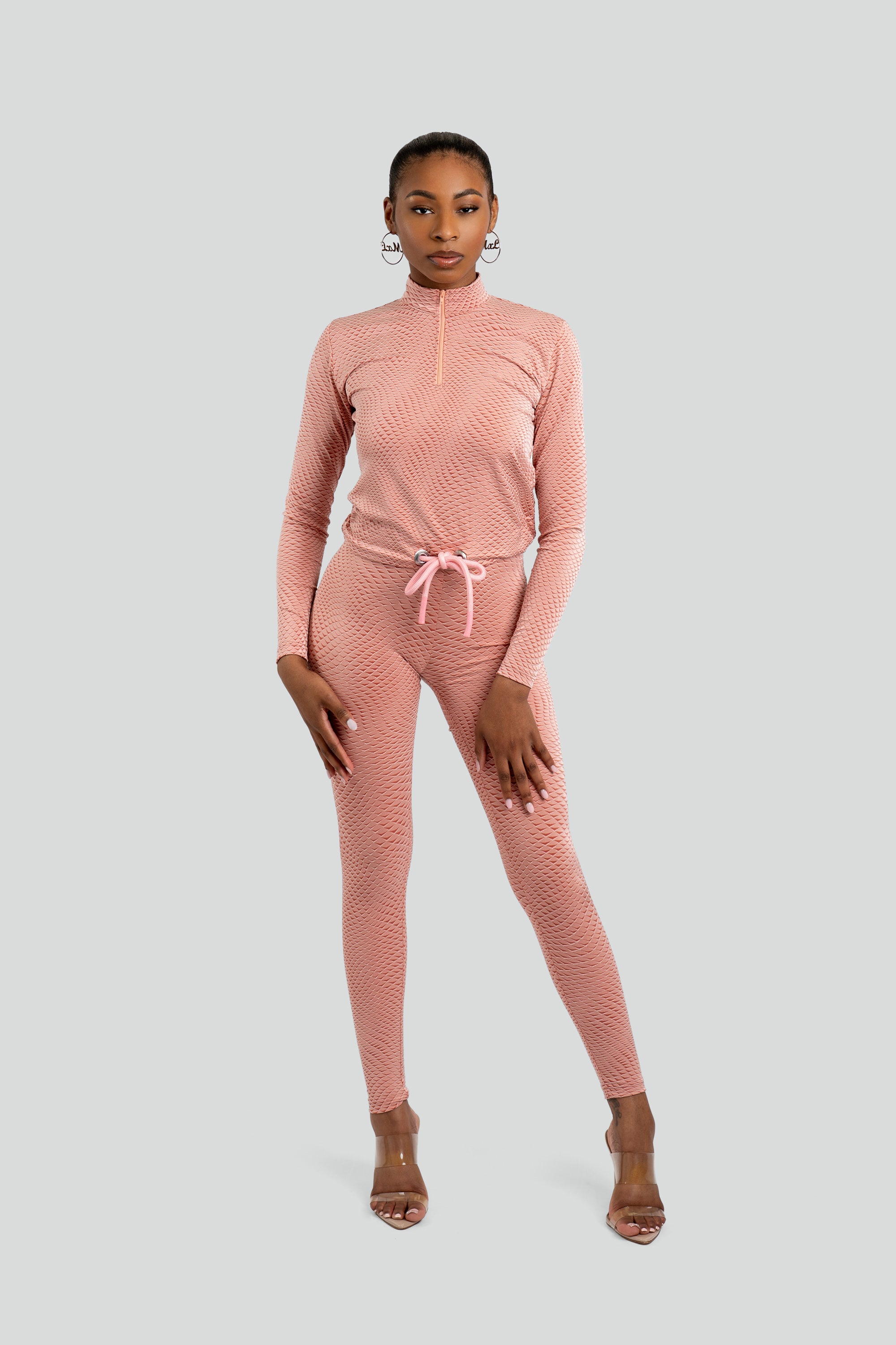 Model wearing a pink patterned workout set on a white background