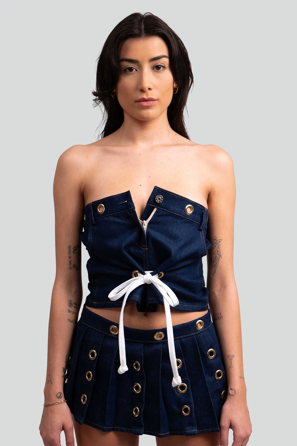 Close up view of structured dark blue denim fabric highlighting the metallic brass grommets and functional front zipper