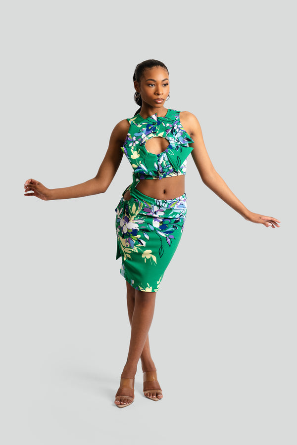 High-waisted body-hugging midi skirt in a vibrant tropical green floral pattern, featuring a side waist cutout and a draped, asymmetrical wrap hemline